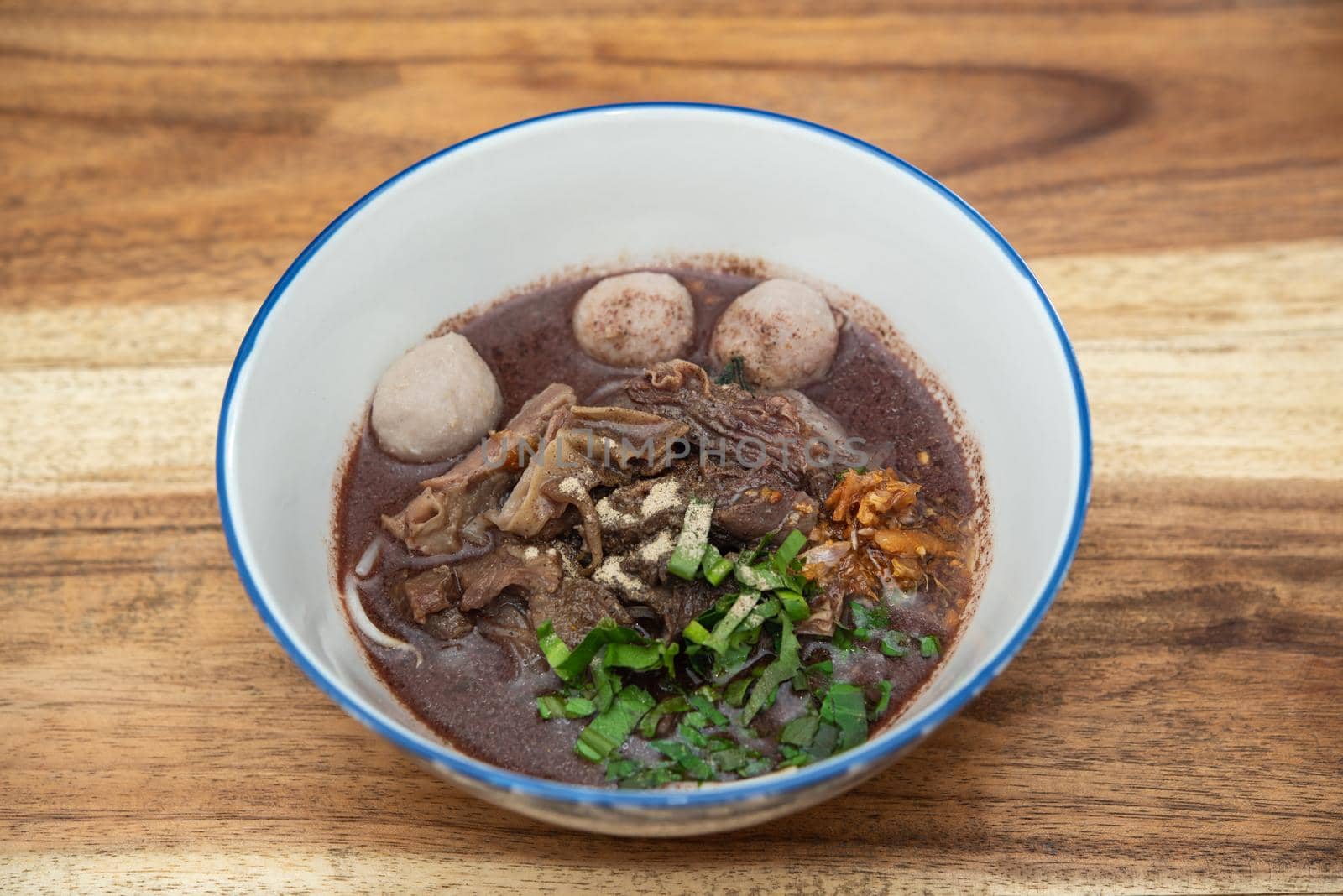 Braised beef clear noodle with meat balls soup stew (Ekaehla meat) with vegetable in bowl for sale at Thai street food market or restaurant in Thailand