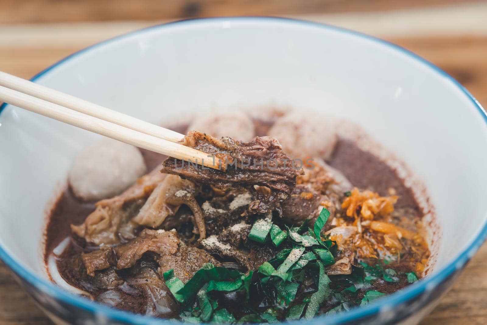 Braised beef clear noodle with meat balls soup stew (Ekaehla meat) with vegetable in bowl for sale at Thai street food market or restaurant in Thailand