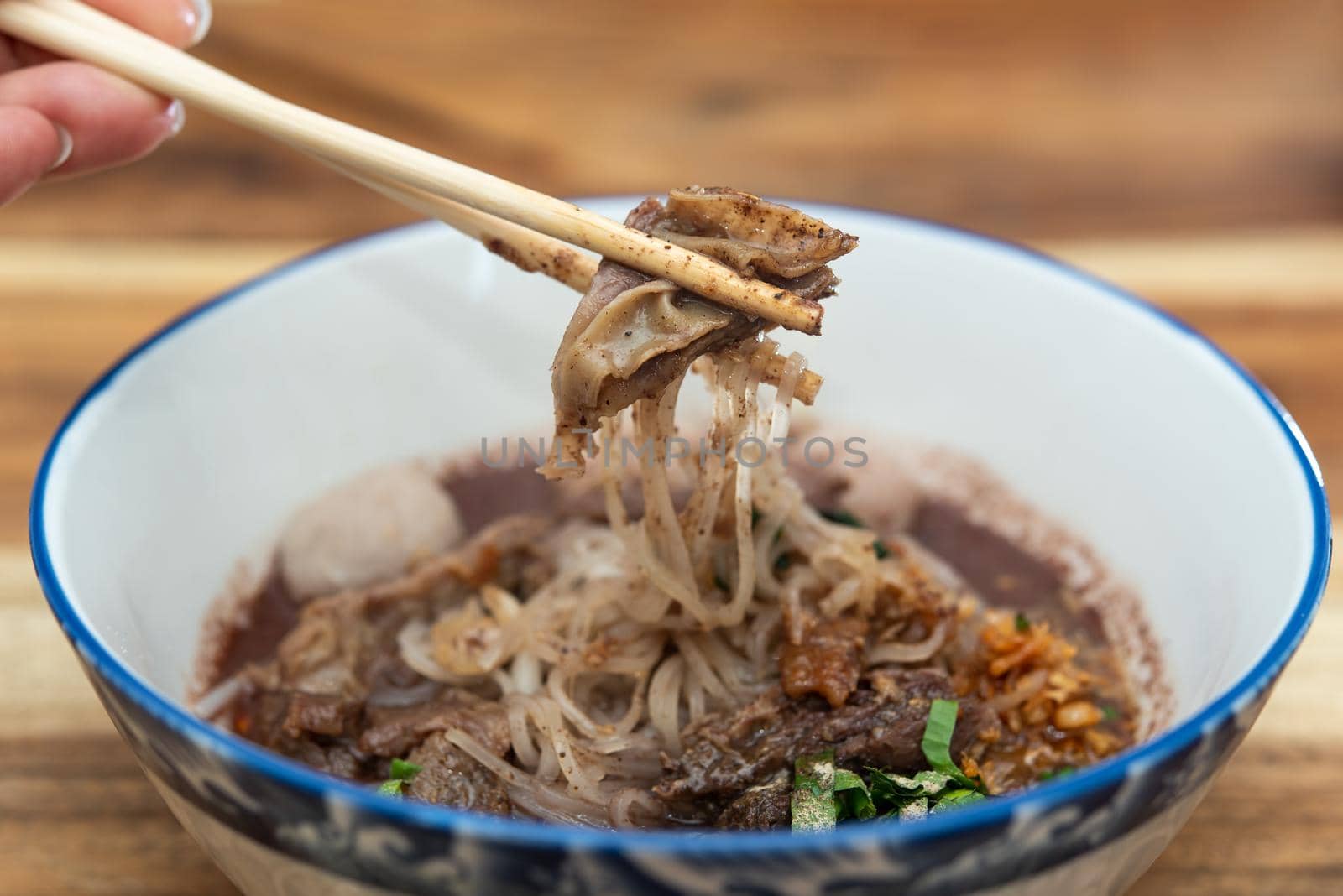 Braised beef clear noodle with meat balls soup stew (Ekaehla meat) with vegetable in bowl for sale at Thai street food market or restaurant in Thailand