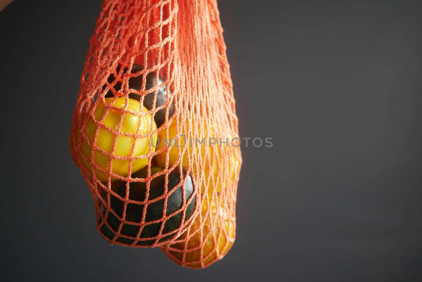 fresh orange fruit and avocado in a shopping bag against black background .