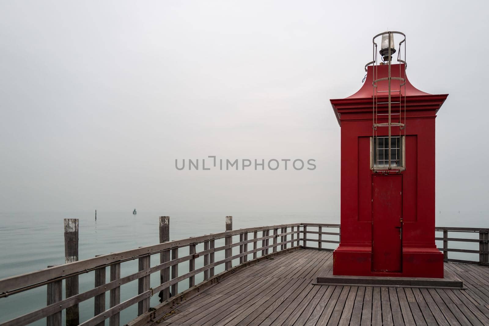 A small red lighthouse with a foggy background.