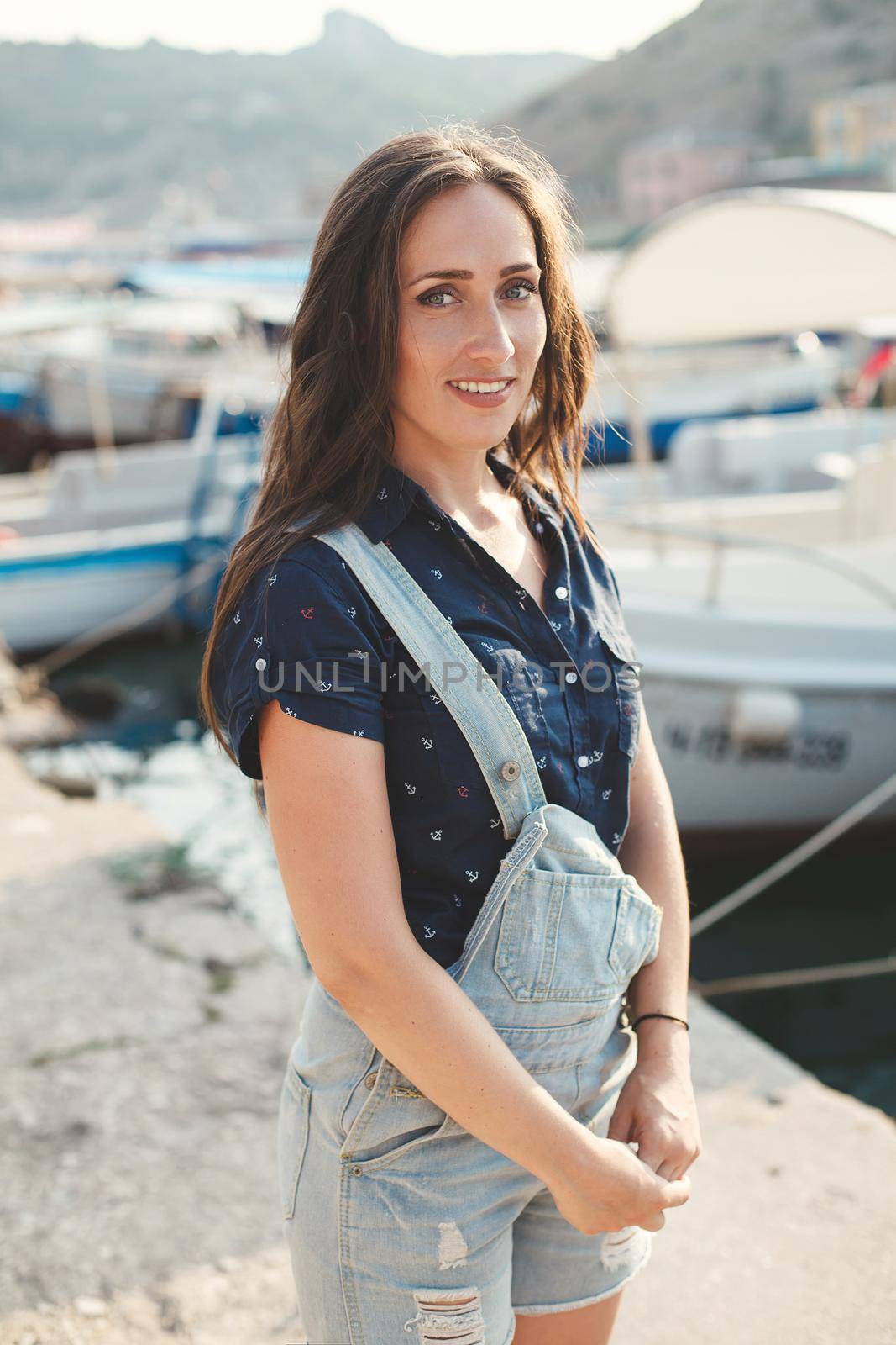 Portrait of a beautiful girl against a wooden pier and yachts