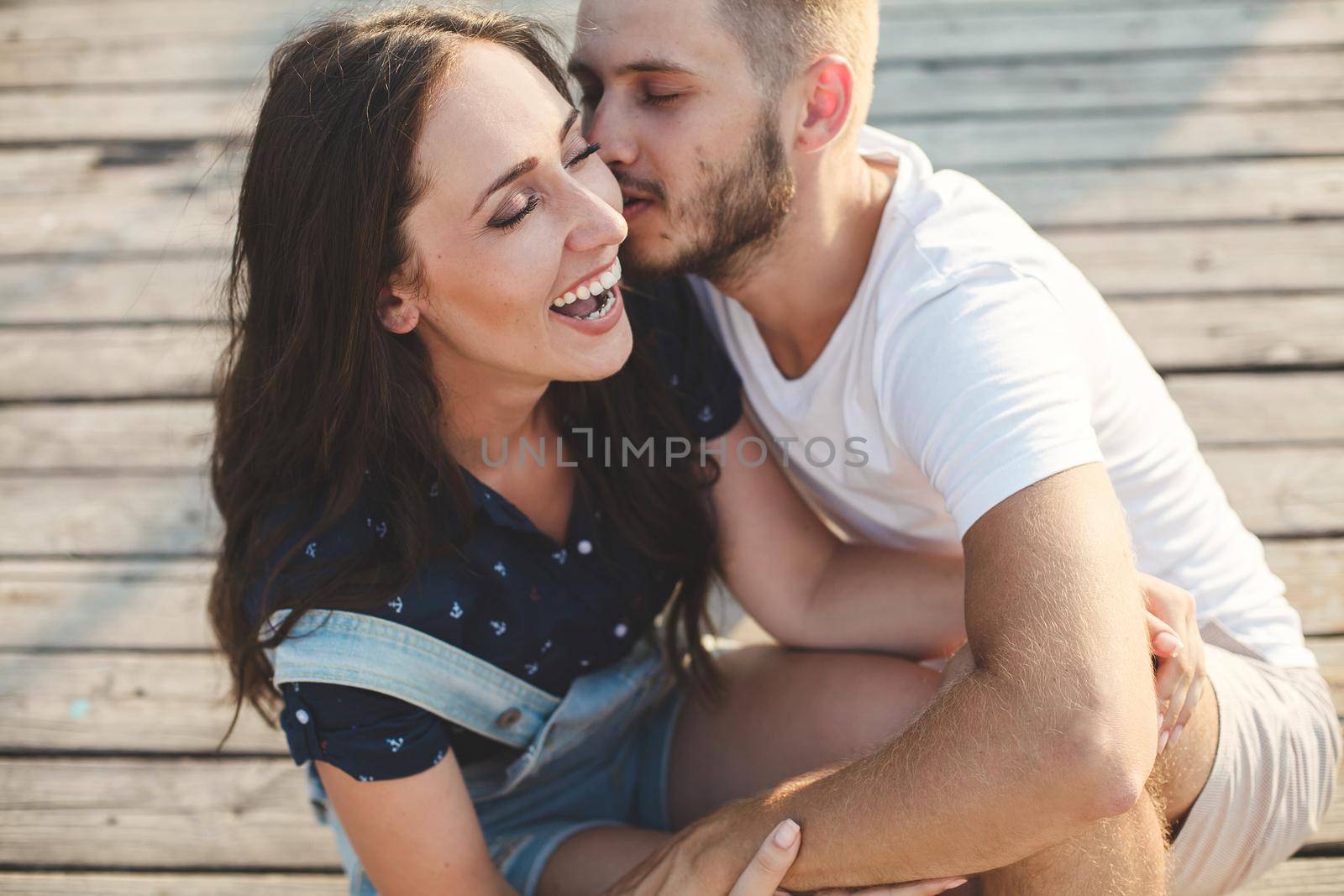 Lovers, guy and girl, close-up laughing against the backdrop of a wooden pier by StudioPeace