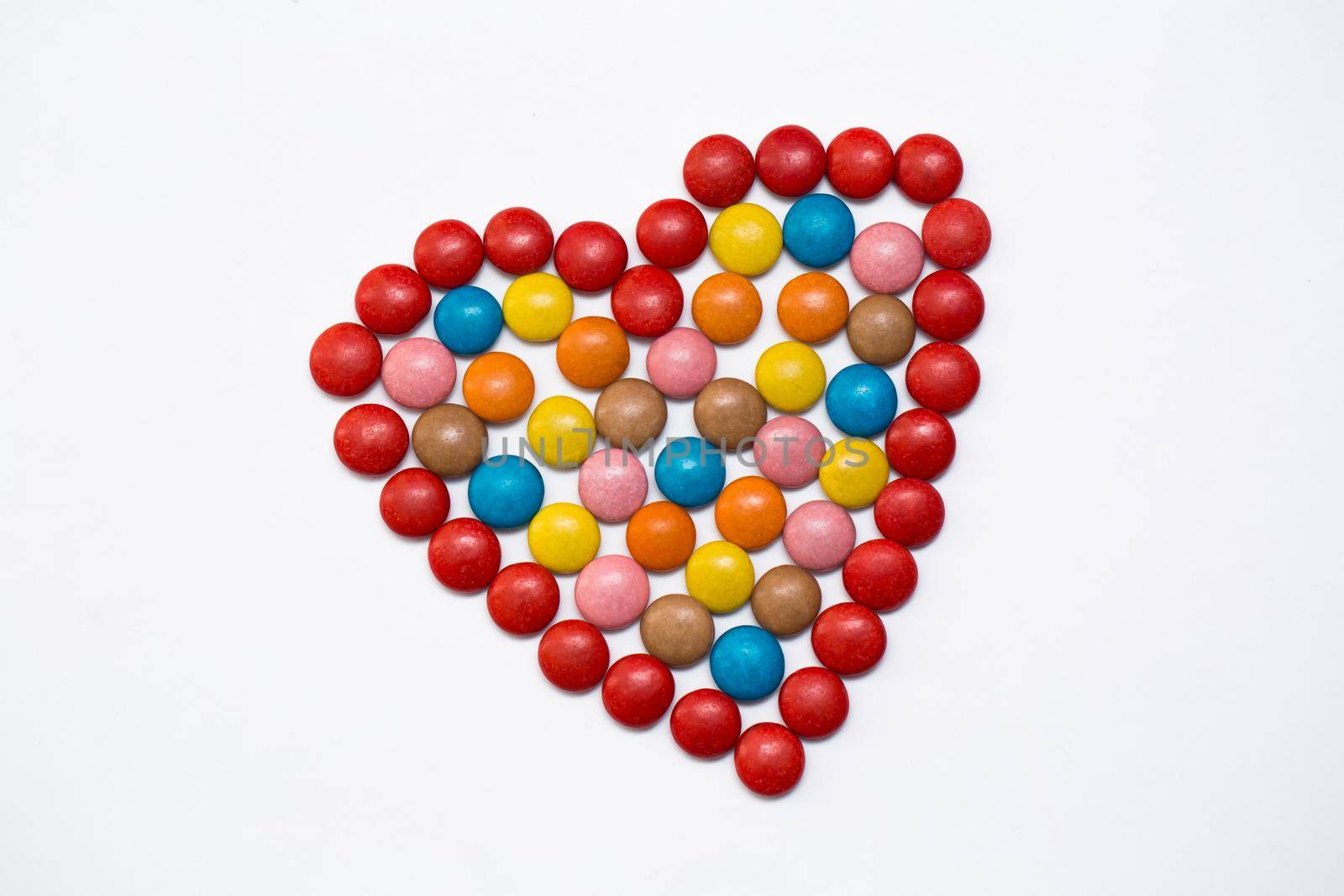 Colorful button chocolate candies in the love shape on white background. by StudioPeace