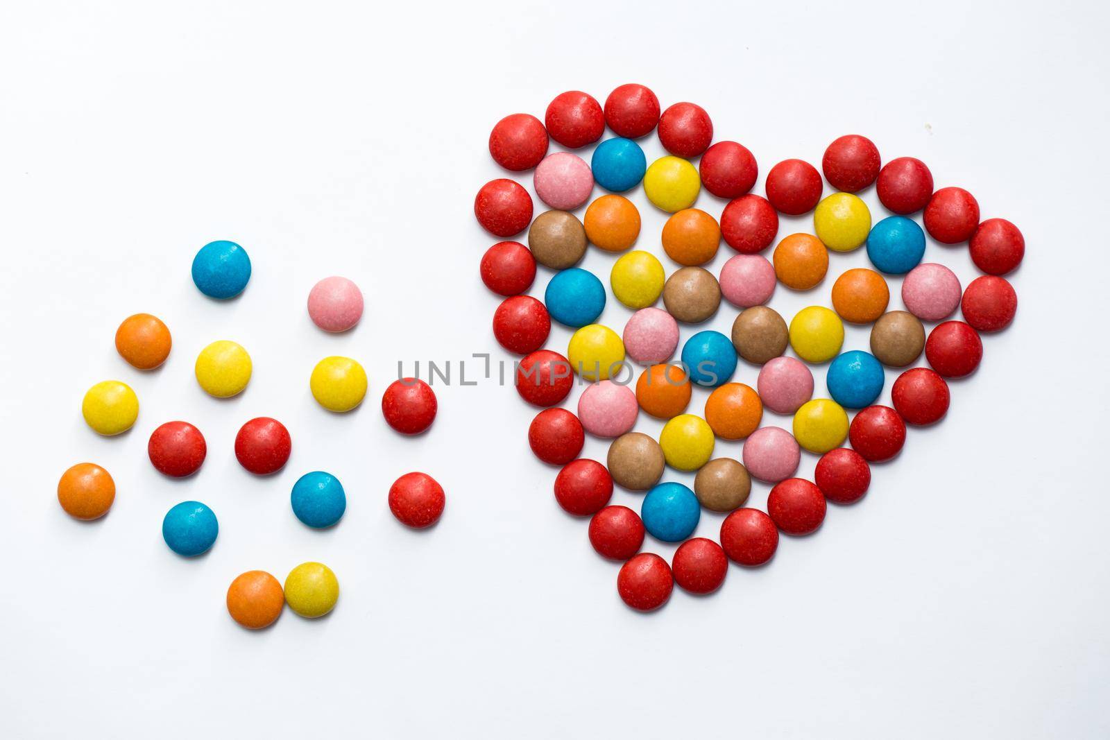 Colorful button chocolate candies in the love shape on white background