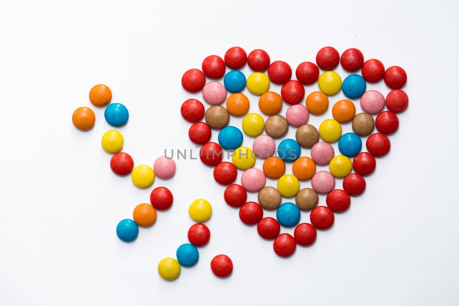 Colorful button chocolate candies in the love shape on white background