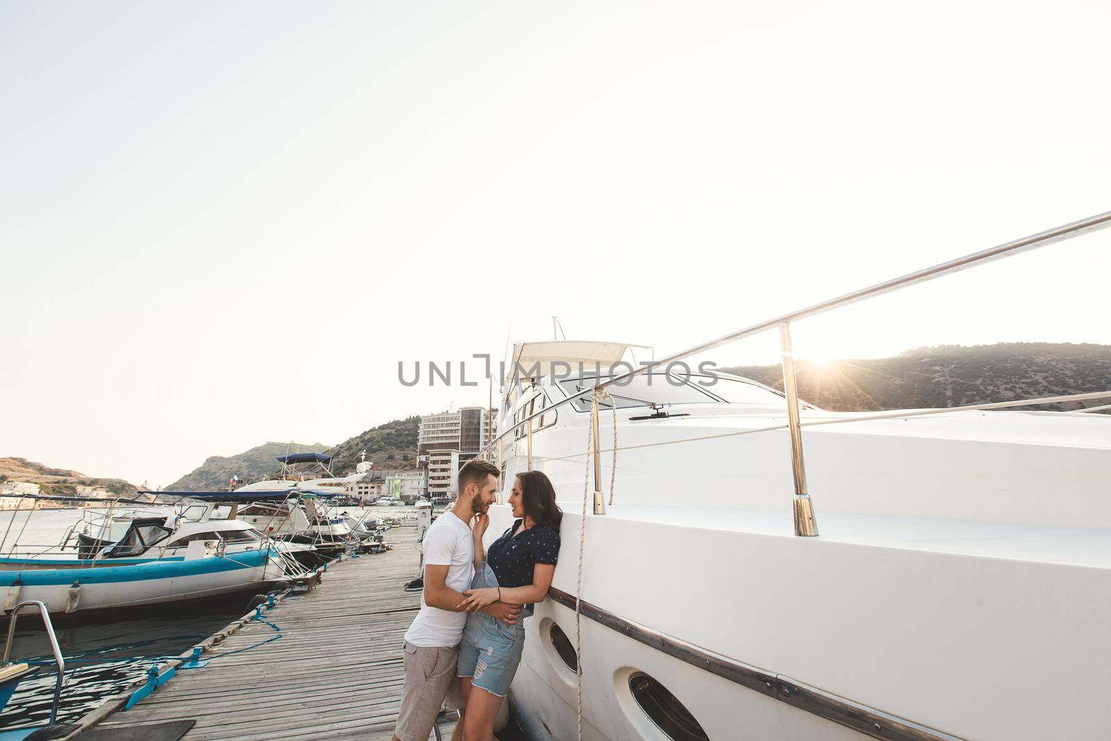 Boy and girl, walk and dance on the pier on the background of yachts and boats
