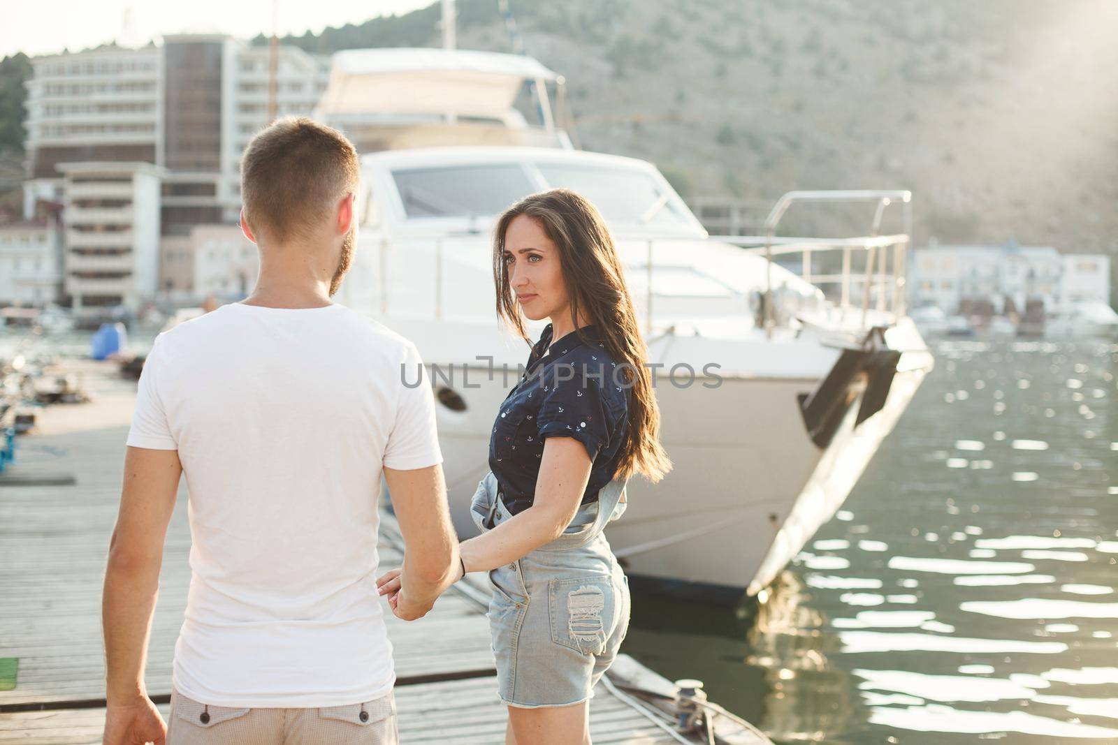Lovers walk on the pier against the backdrop of yachts and boats by StudioPeace