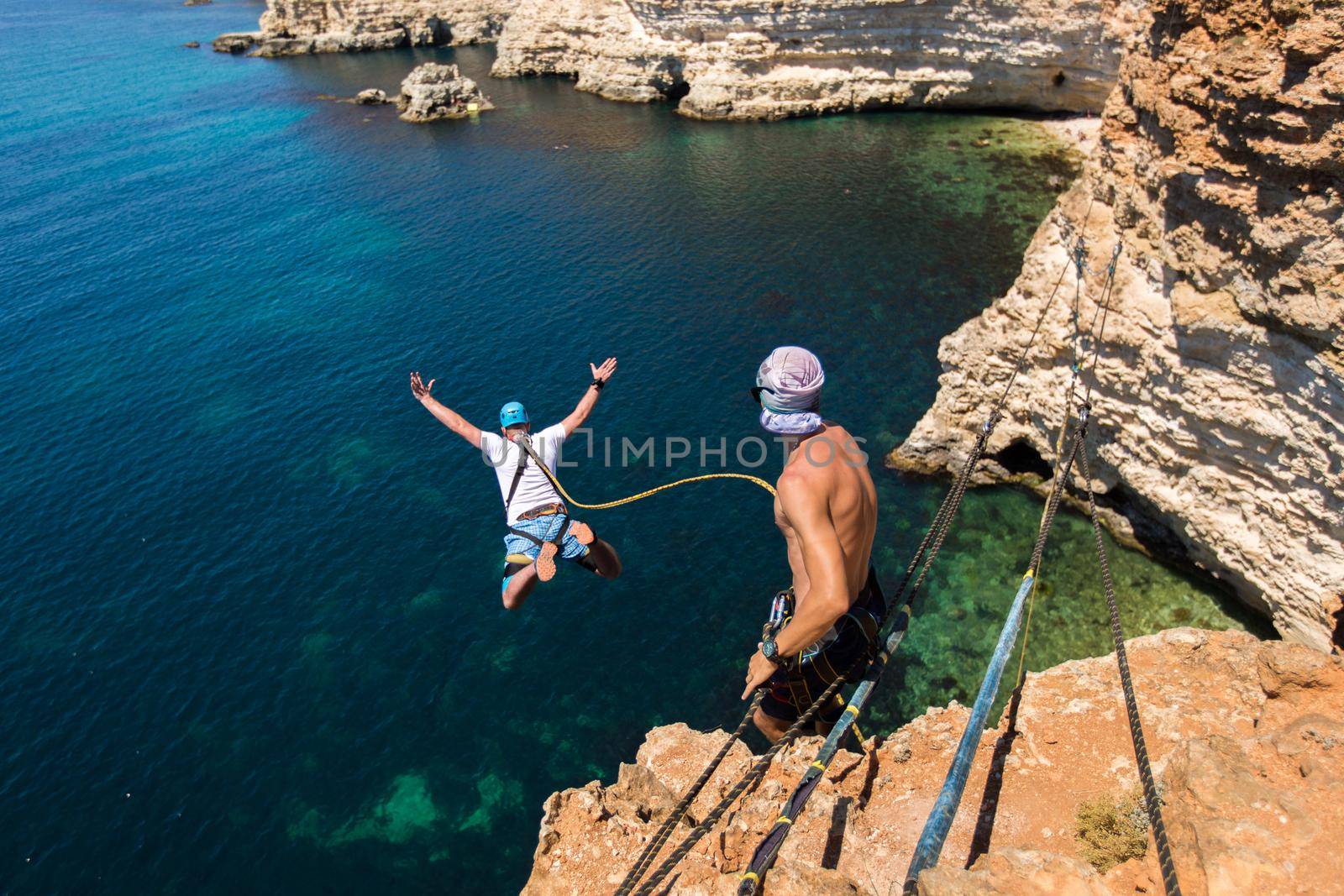 Rope jumping off a cliff with a rope in the water. The ocean. Sea. Mountain.