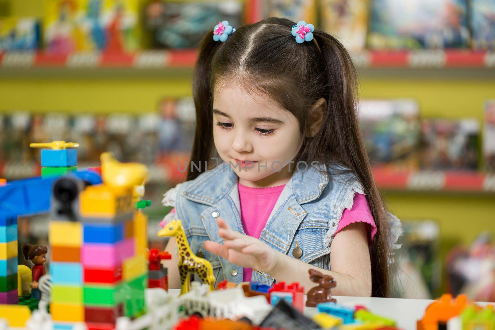Little girl playing with building blocks in the store. by StudioPeace