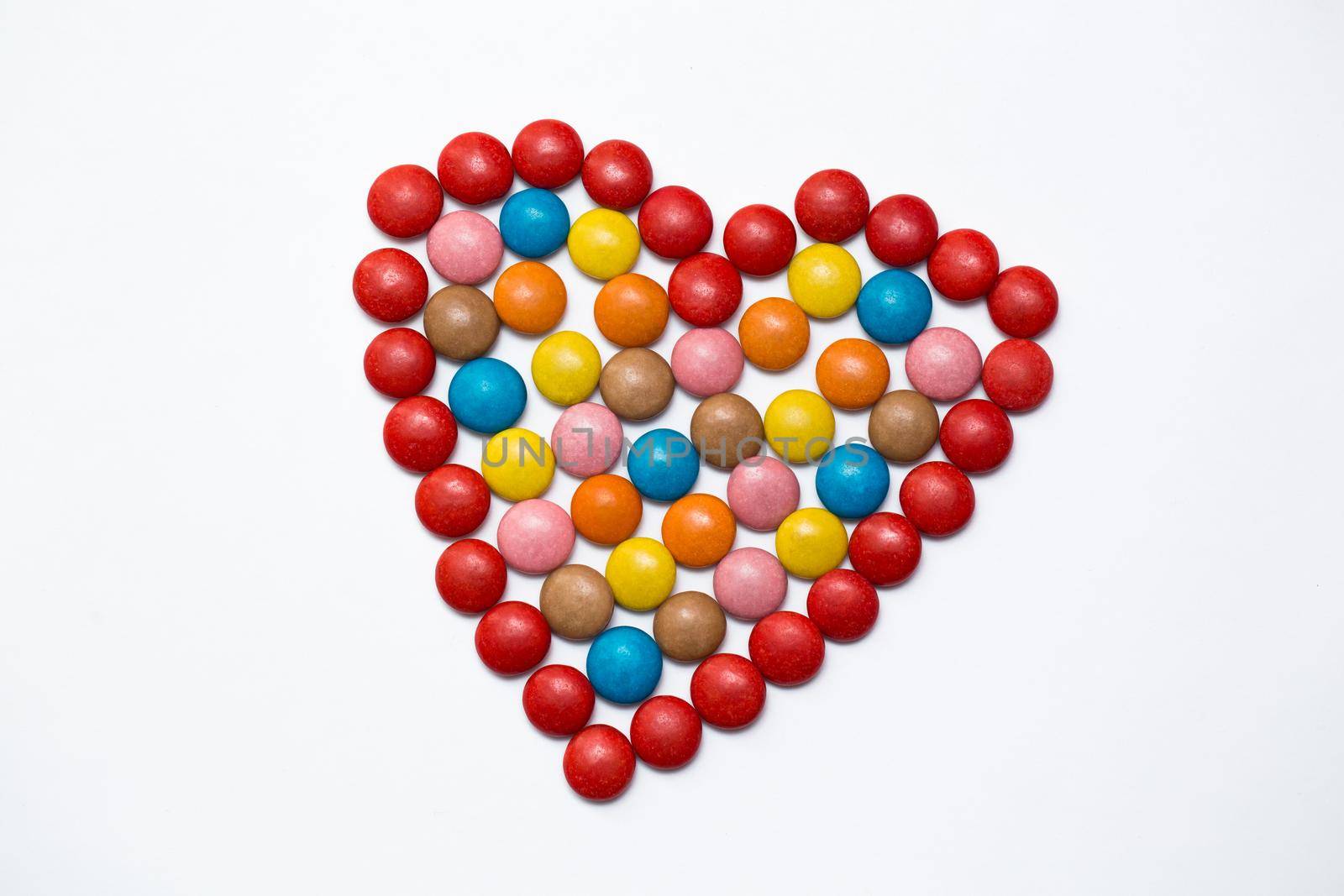 Colorful button chocolate candies in the love shape on white background. by StudioPeace