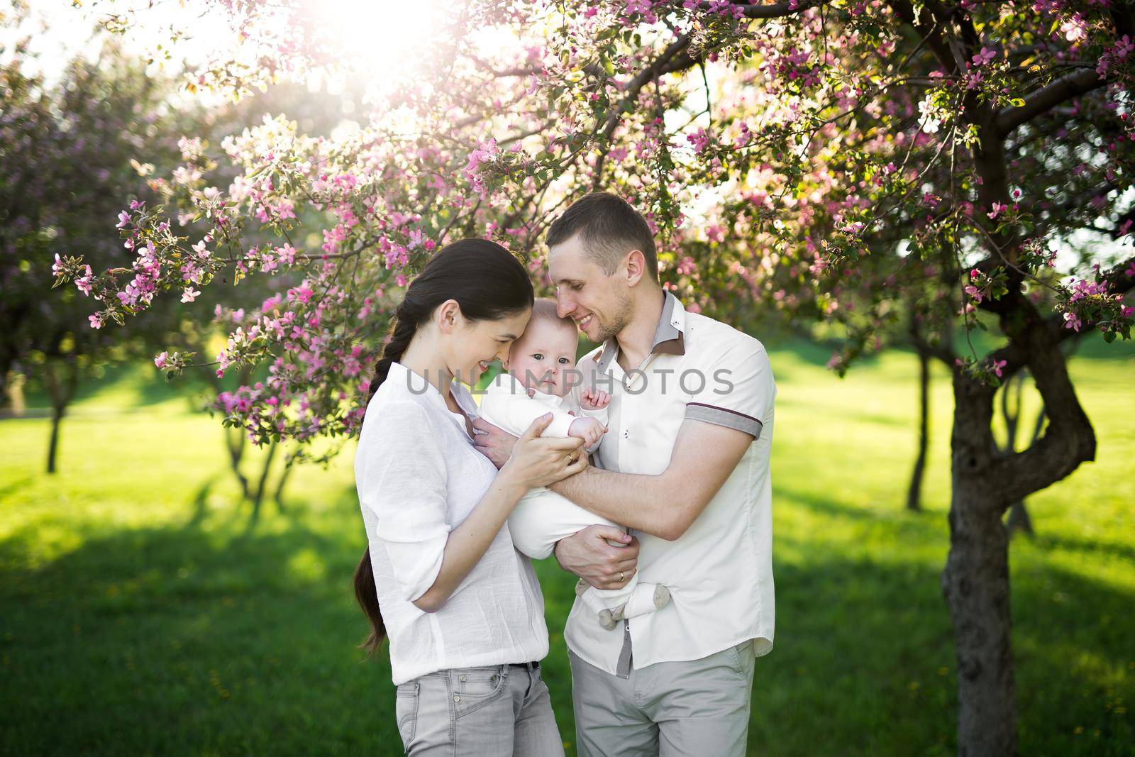 Portrait of a young family with a child. Happy young family spending time outdoor on a summer day. Happiness and harmony in family life. Happy family concept.