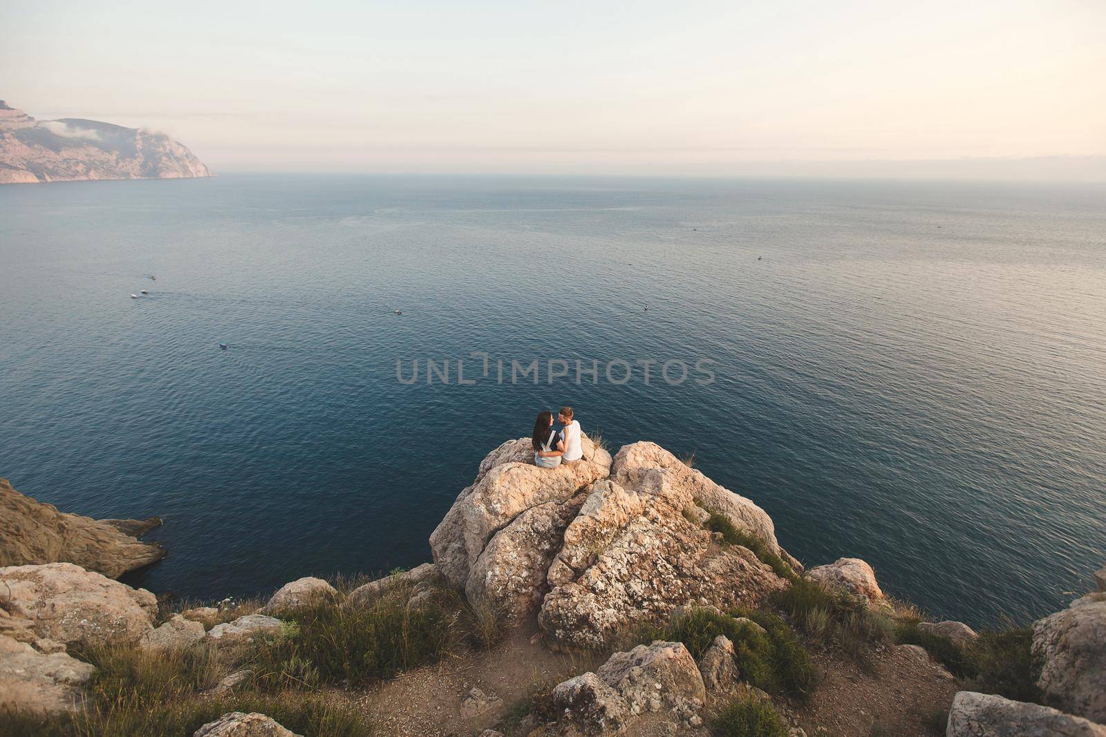 Lovers, guy and girl, on the edge of the cliff against the backdrop of mountains and ocean by StudioPeace