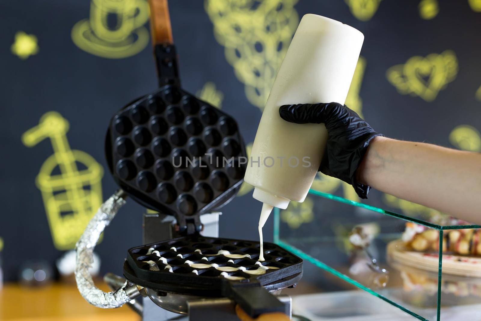 Pouring dough on waffle maker. Preparing Hong Kong waffle. by StudioPeace