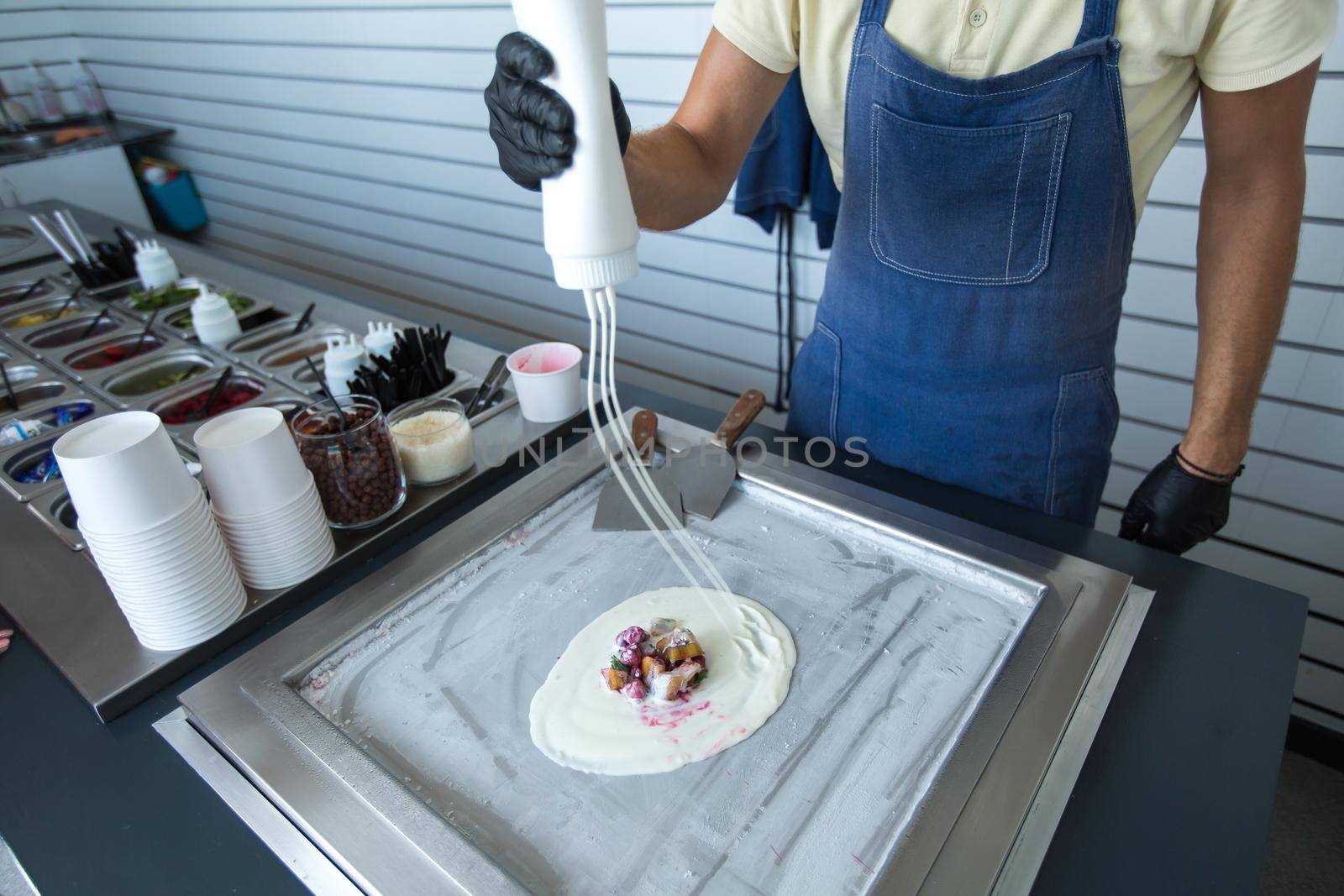 Stir-fried ice cream rolls at freeze pan. Rolled ice cream, hand made ice cream dessert. Fried ice cream machine with steel chilled pan by StudioPeace