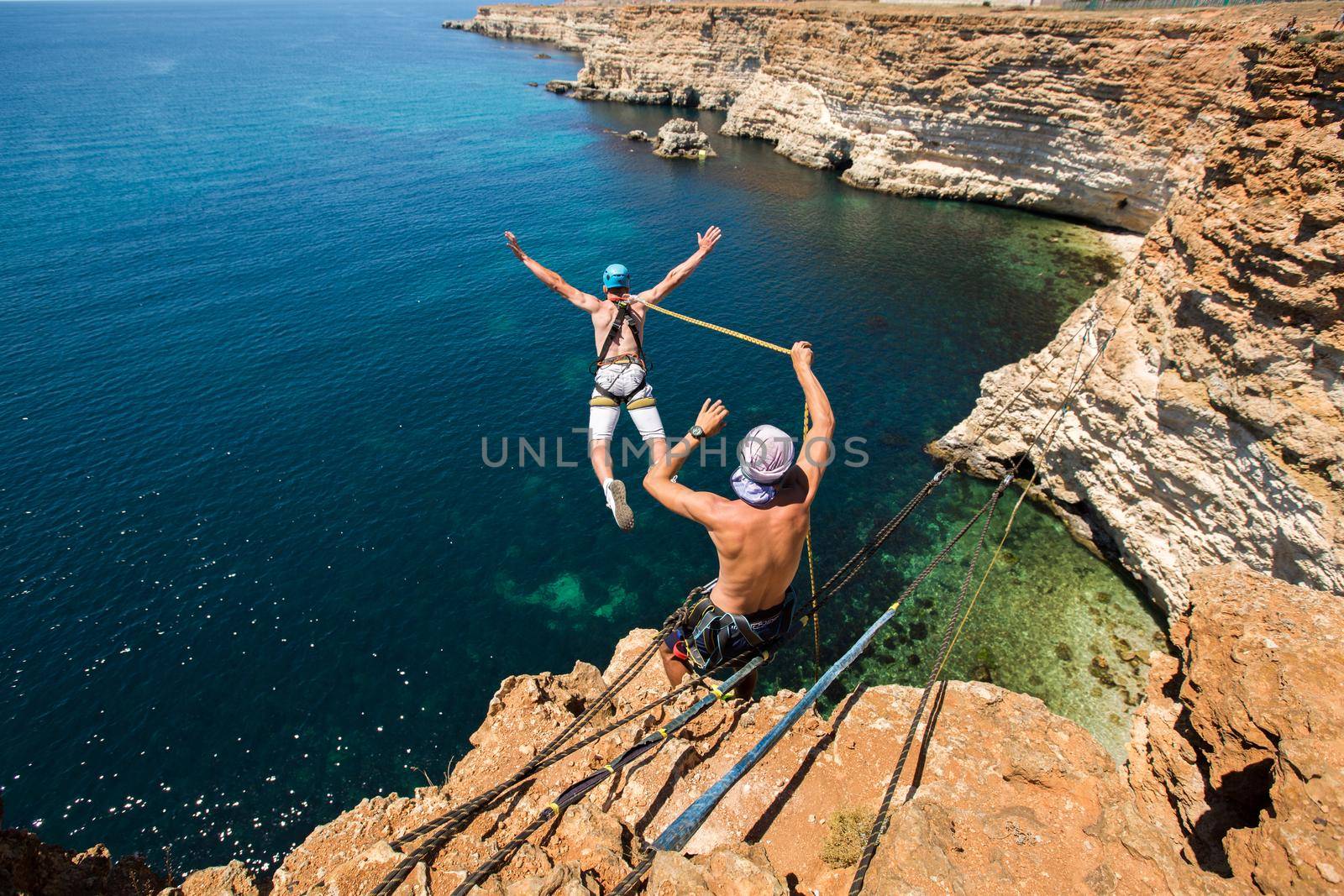 Rope jumping off a cliff with a rope in the water. The ocean. Sea. Mountain by StudioPeace