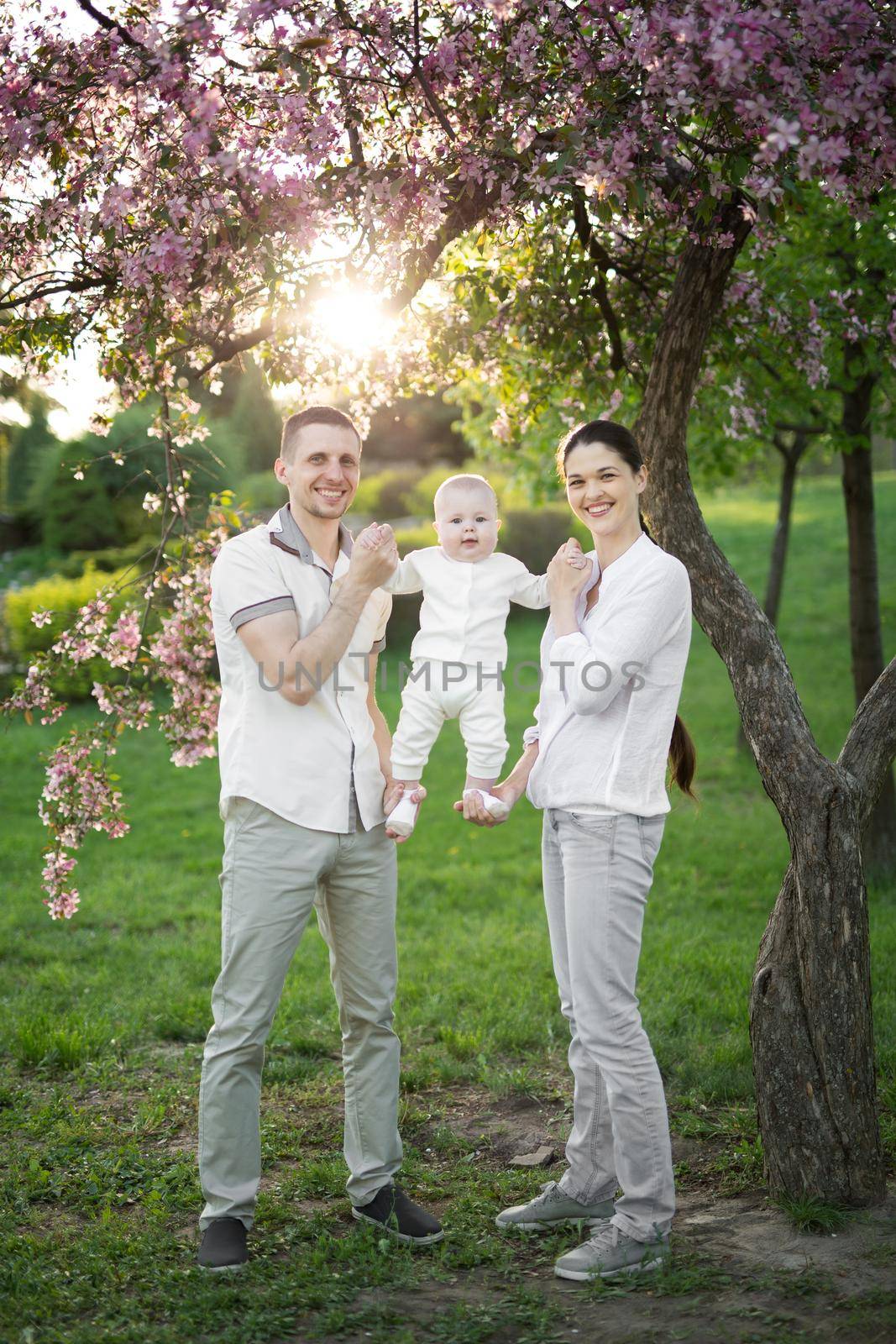 Portrait of a young family with a child. Happy young family spending time outdoor on a summer day. Happiness and harmony in family life. Happy family concept by StudioPeace