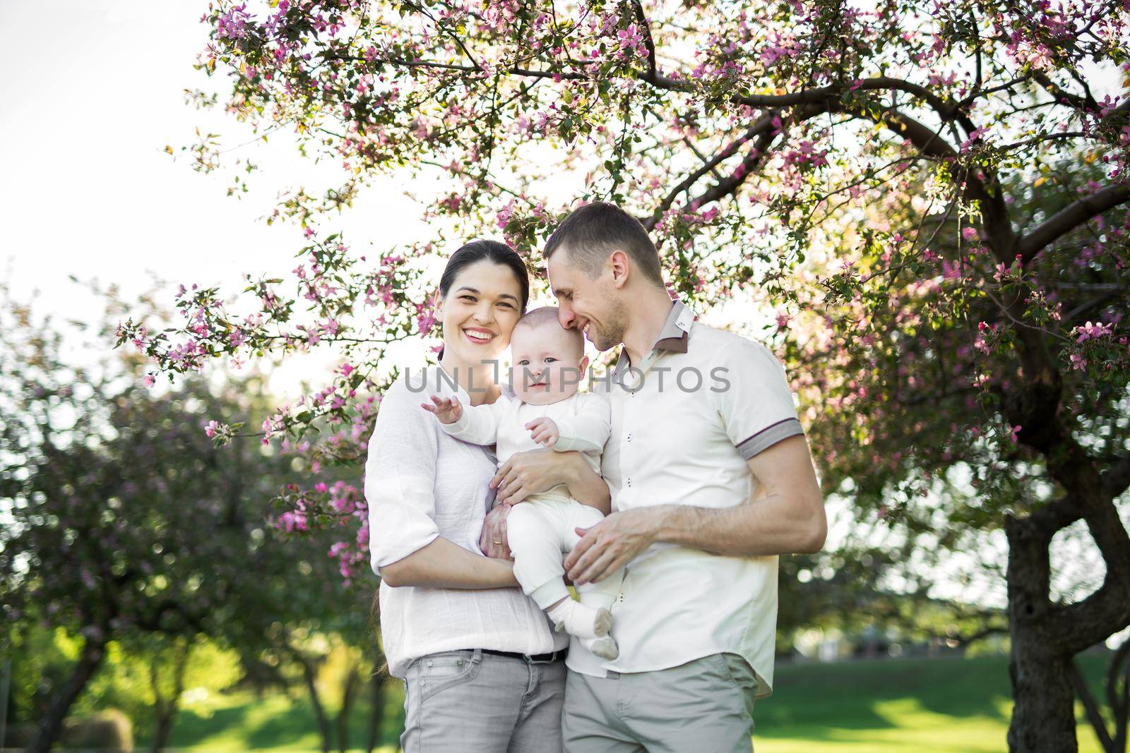 Portrait of a young family with a child. Happy young family spending time outdoor on a summer day. Happiness and harmony in family life. Happy family concept.