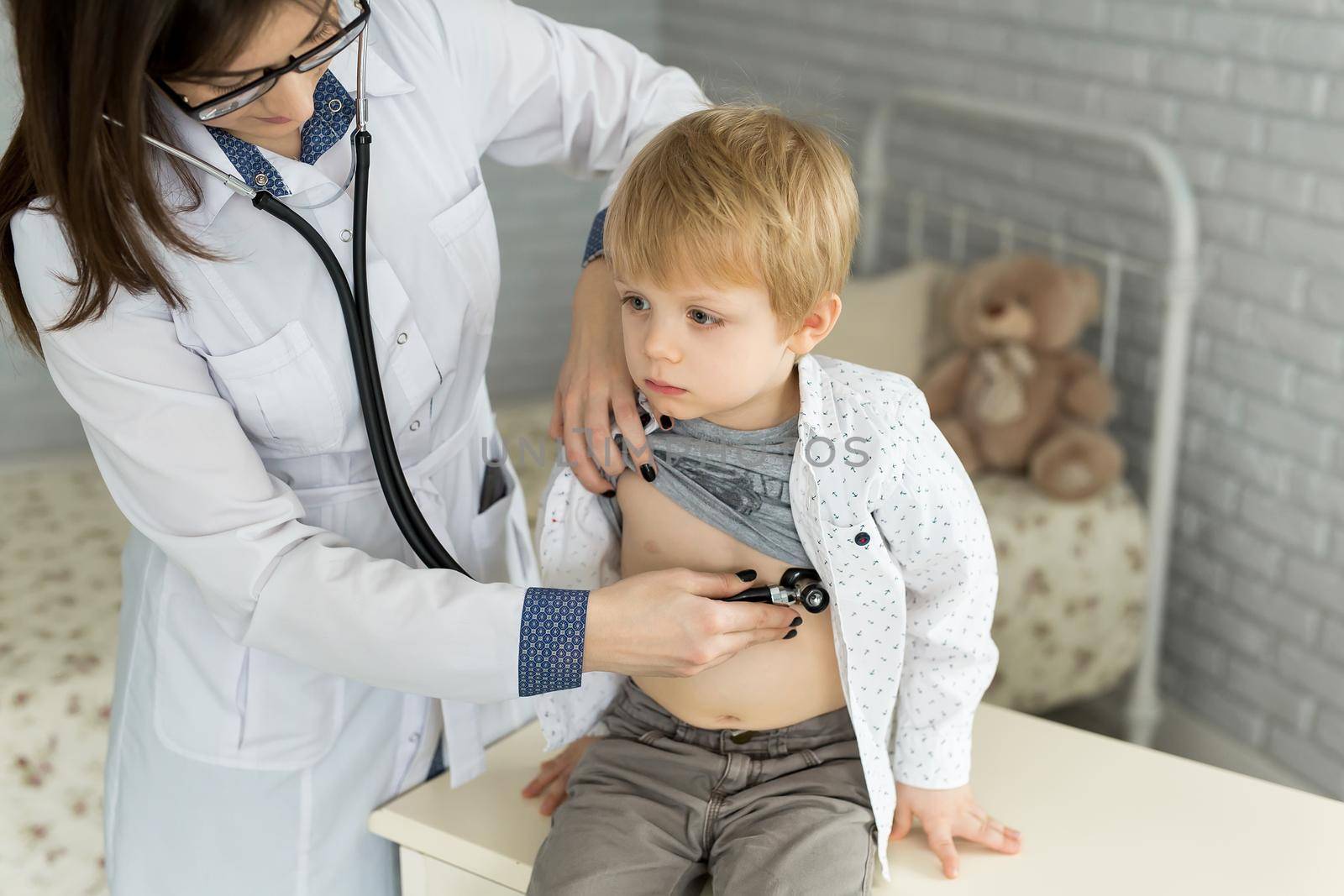 Professional general medical pediatrician doctor in white uniform gown listen lung and heart sound of child patient with stethoscope.