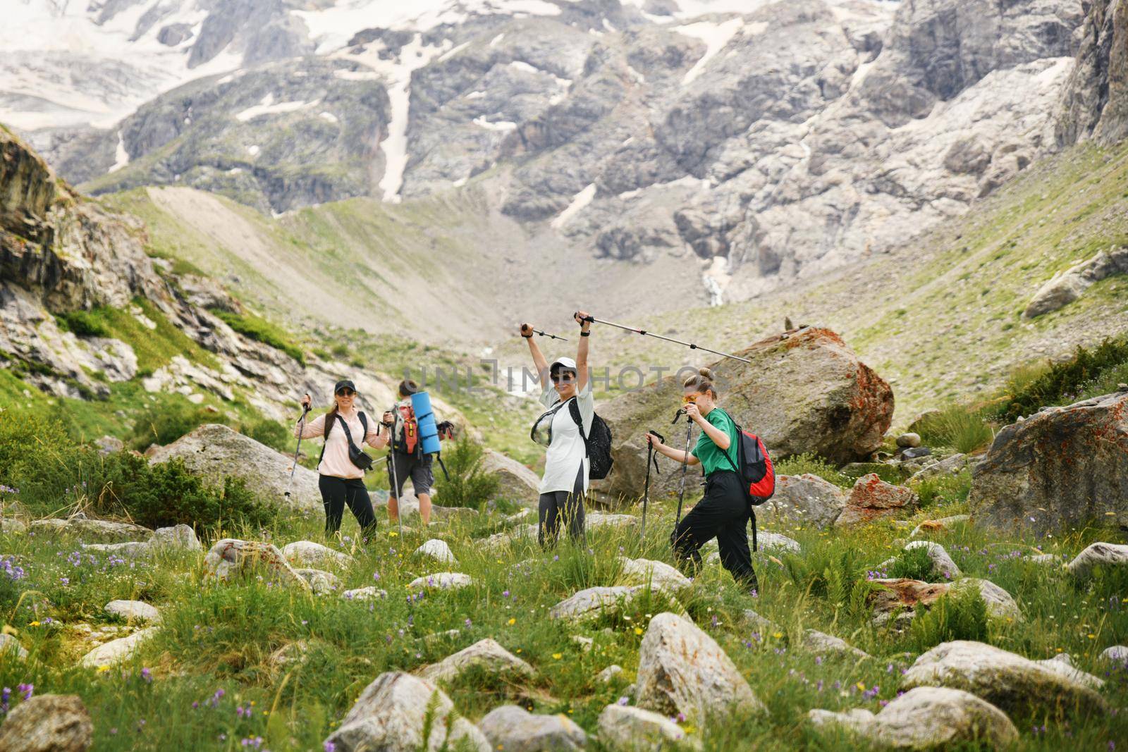 Women with backpacks and scandinavian sticks climb the mountains in Caucasus