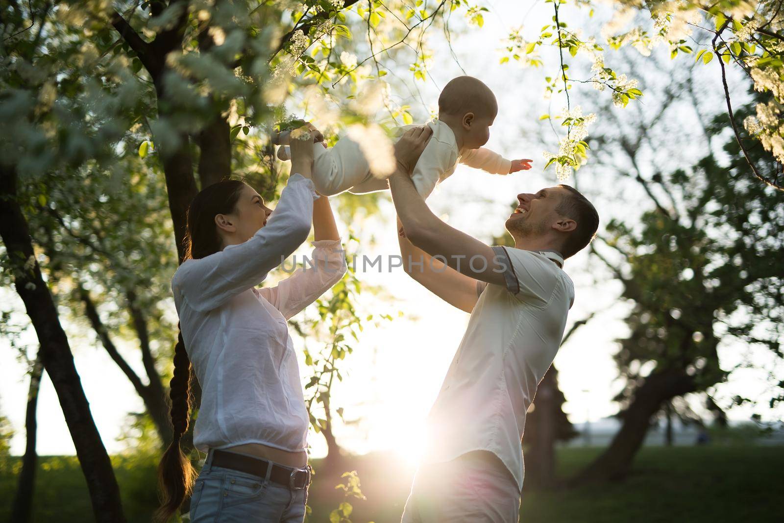 Happy man and woman playing with baby outdoors