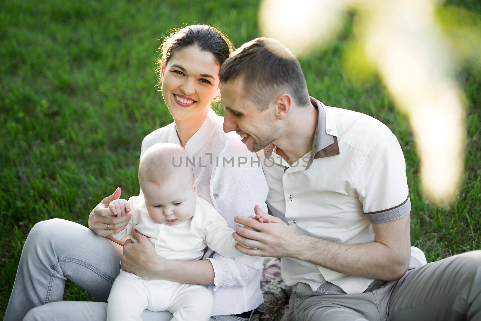 Portrait Beautiful Mother, Father And Baby outdoors. Happy family on a summer meadow