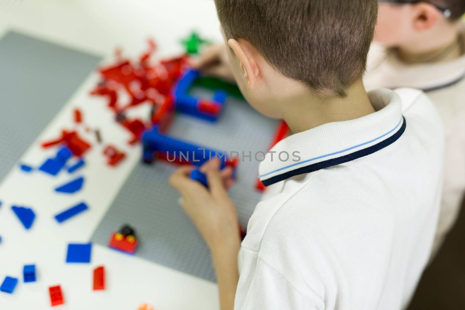 Children play in the designer at the table. Two boys play together with colored plastic blocks in the gaming center, school.