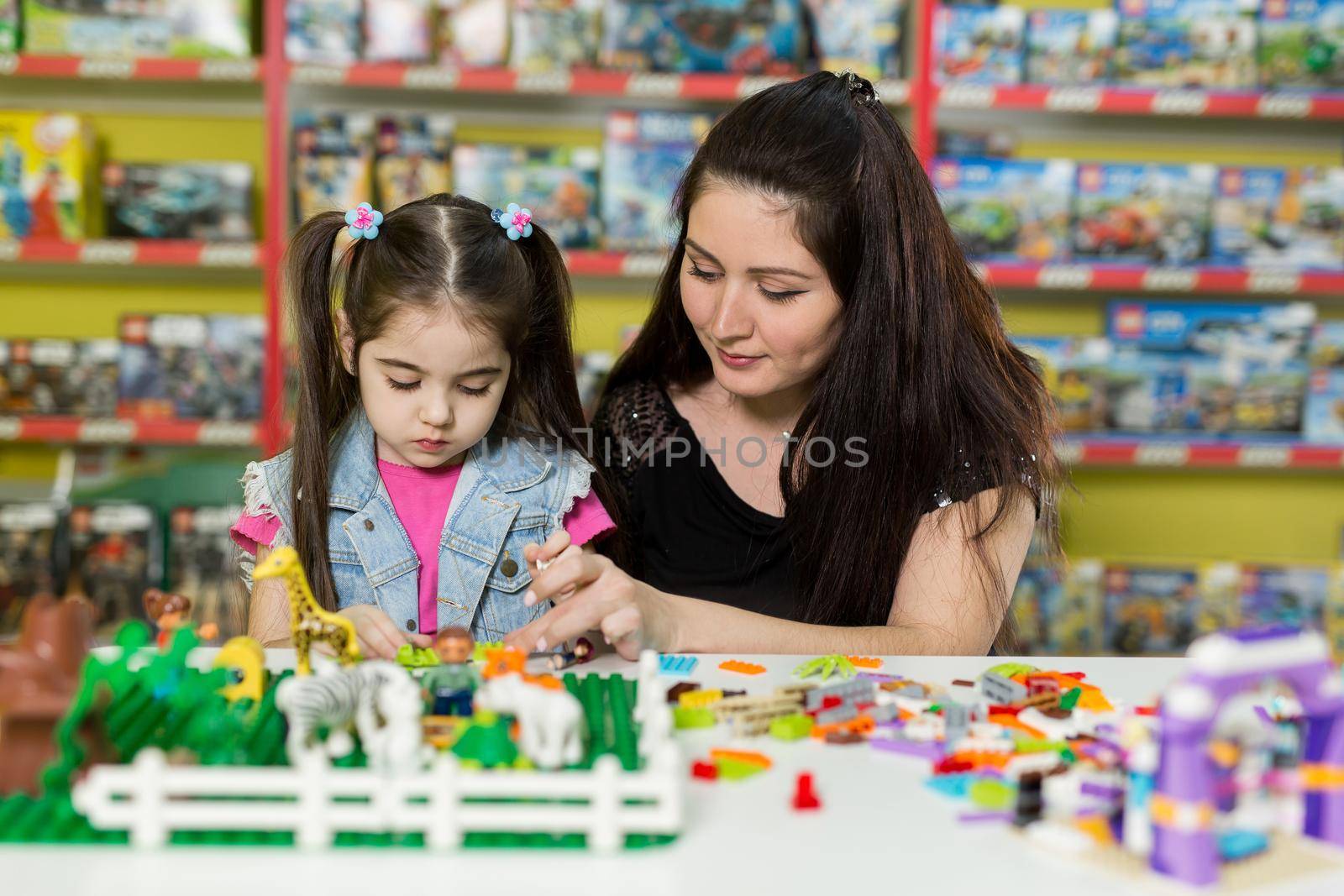 Mother with a little daughter playing with blocks