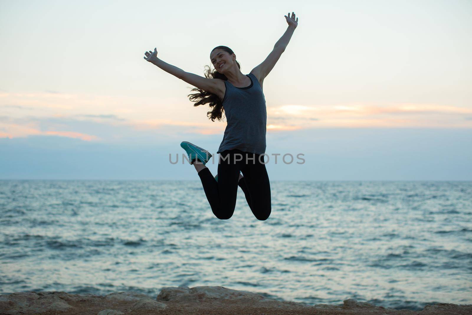 Sport girl jumping on beach at sunset. by StudioPeace