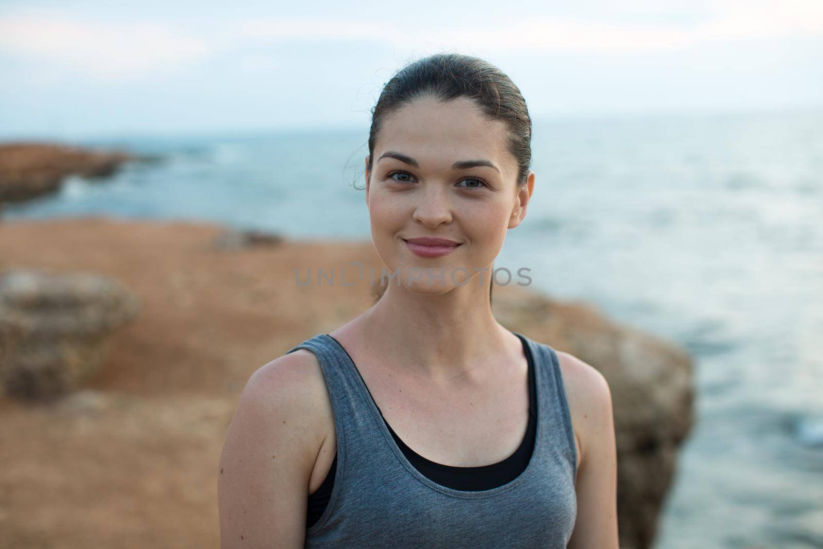 Smiling female jogger on the sea at sunset