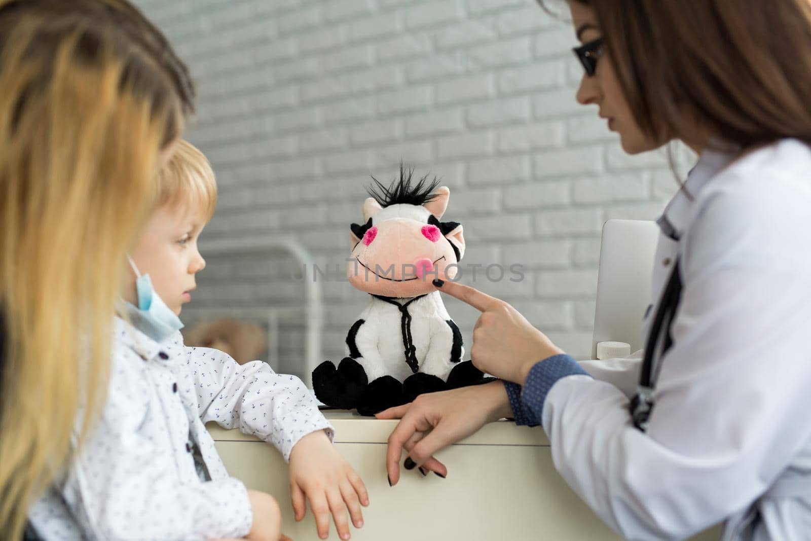 A boy playing doctor with a soft cow toy. by StudioPeace