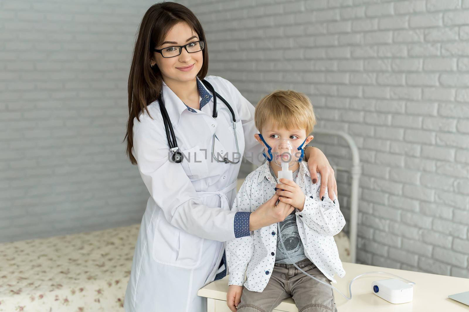 Medical doctor applying medicine inhalation treatment on a little boy with asthma inhalation therapy by the mask of inhaler.
