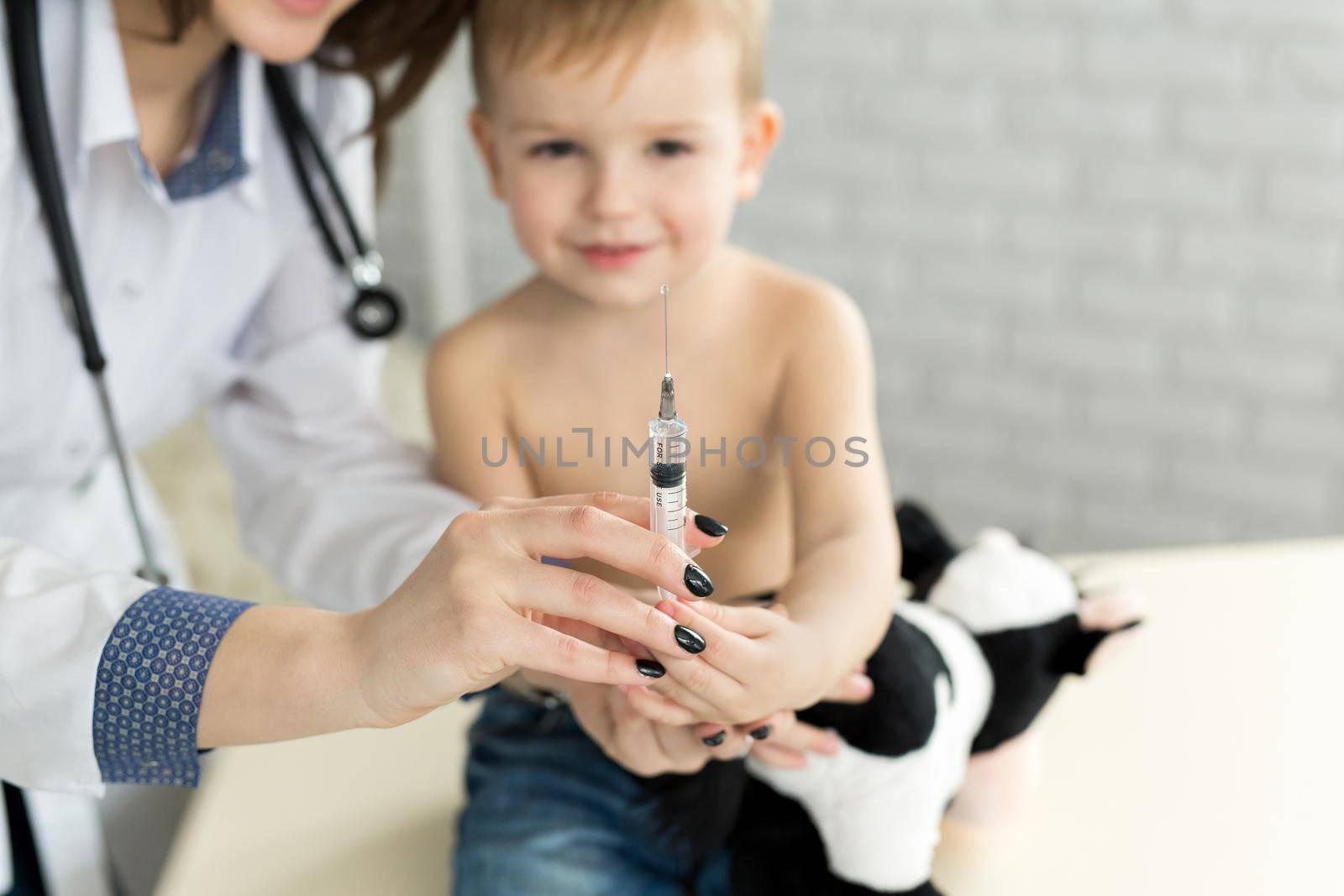 Doctor pediatrician plays before the injection with the boy by StudioPeace