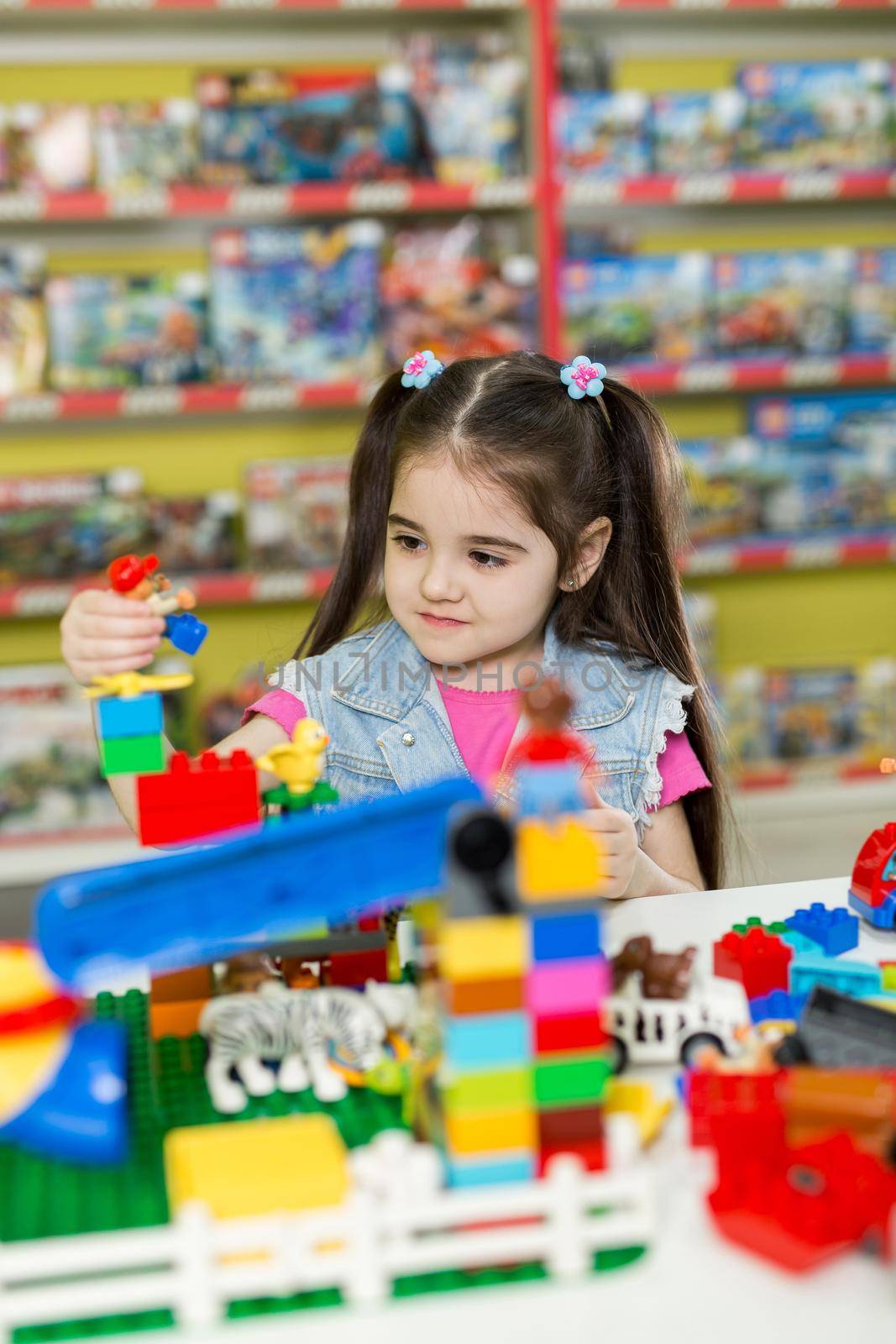 Little girl playing with building blocks in the store
