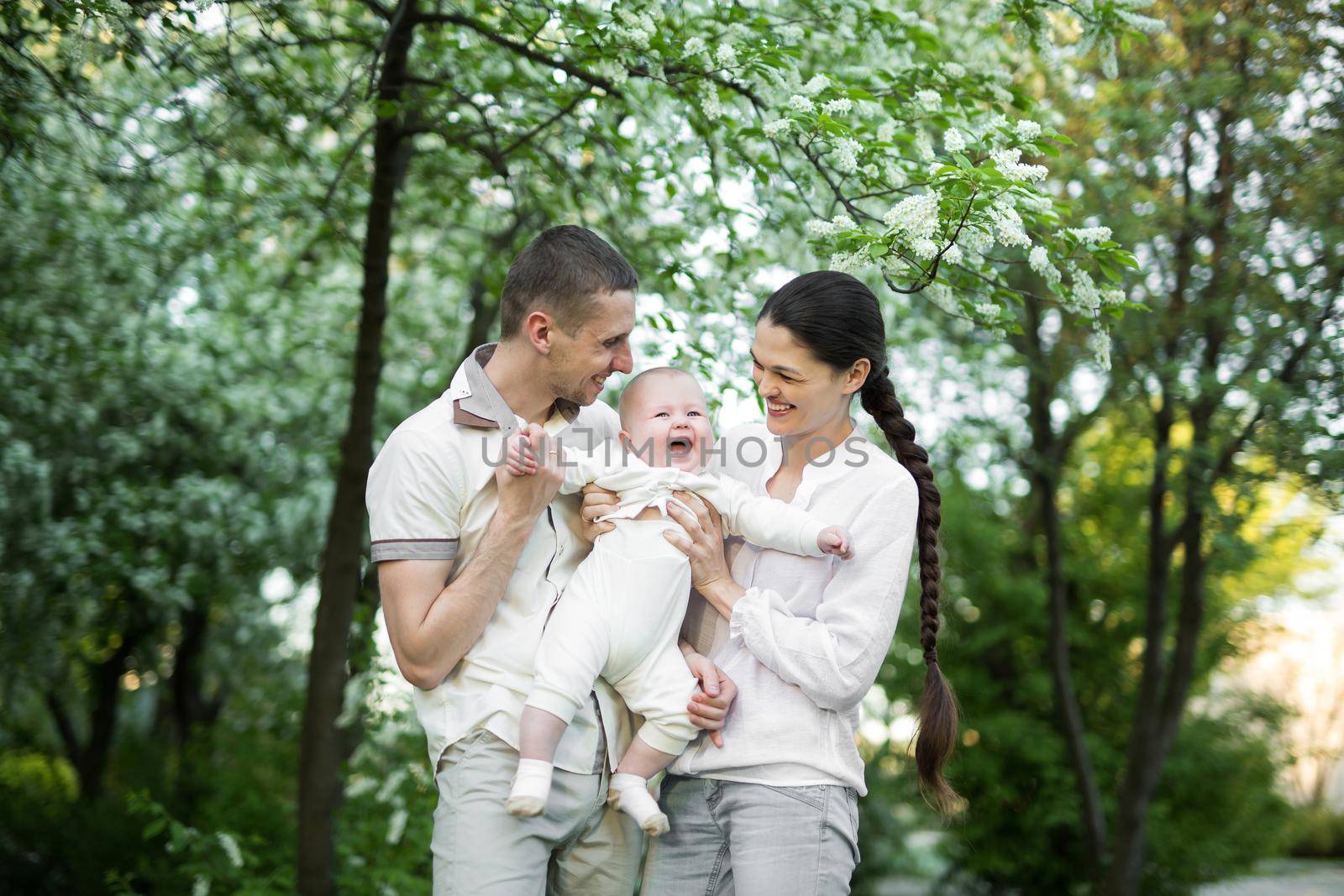 Portrait of a young family with a child. Happy young family spending time outdoor on a summer day. Happiness and harmony in family life. Happy family concept.