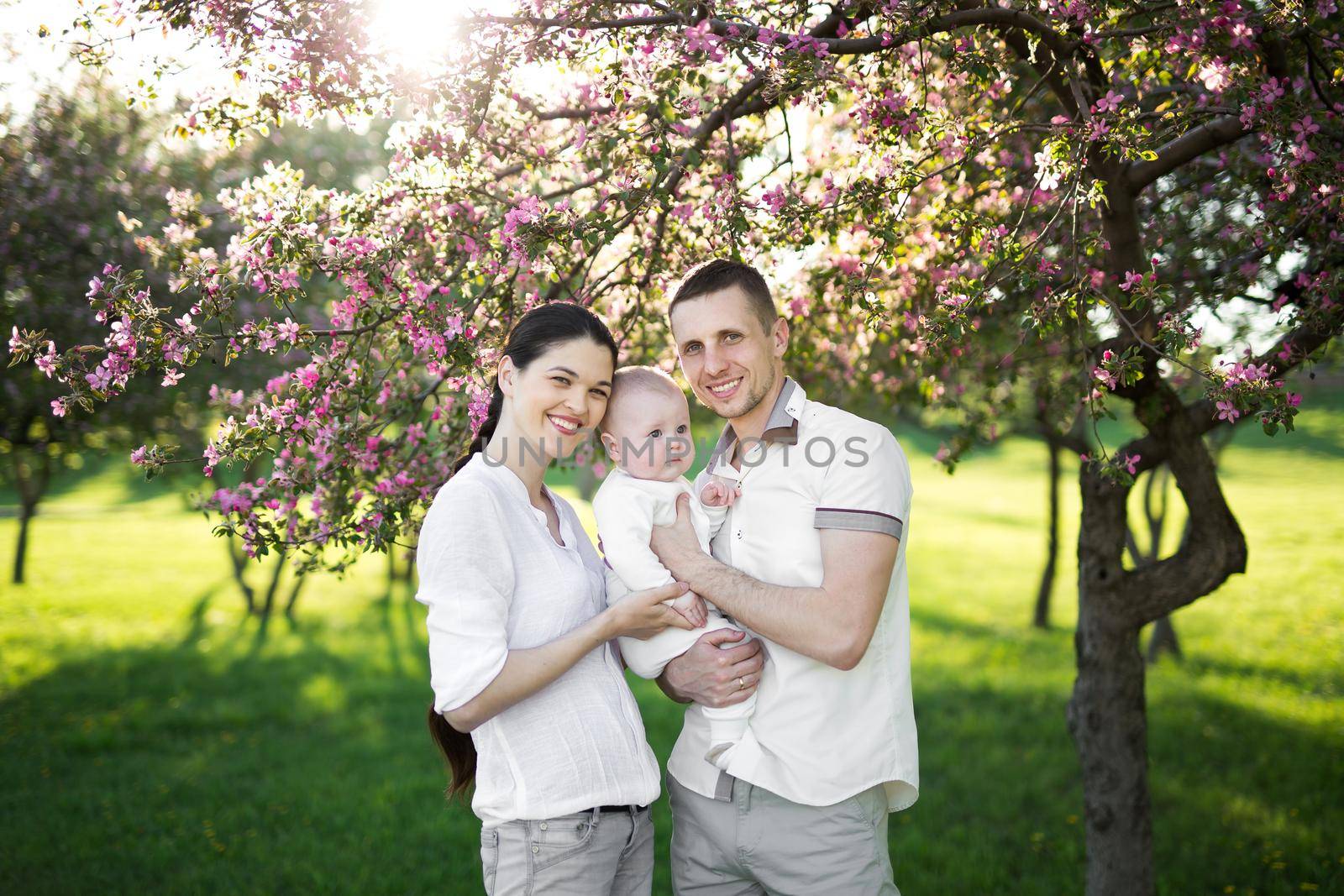 Portrait of a young family with a child. Happy young family spending time outdoor on a summer day. Happiness and harmony in family life. Happy family concept.