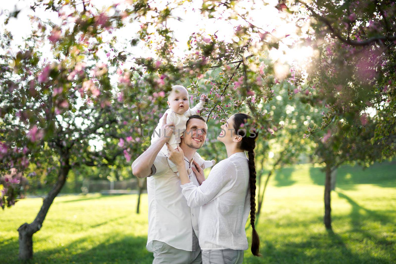 Happy man and woman playing with baby outdoors