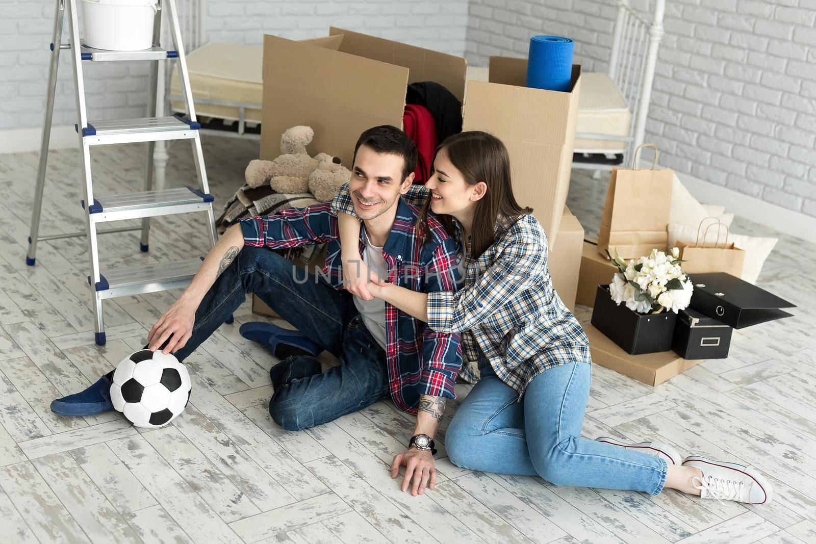Young couple in a new home relaxing on the background of big boxes. Concept housewarming, began living together by StudioPeace