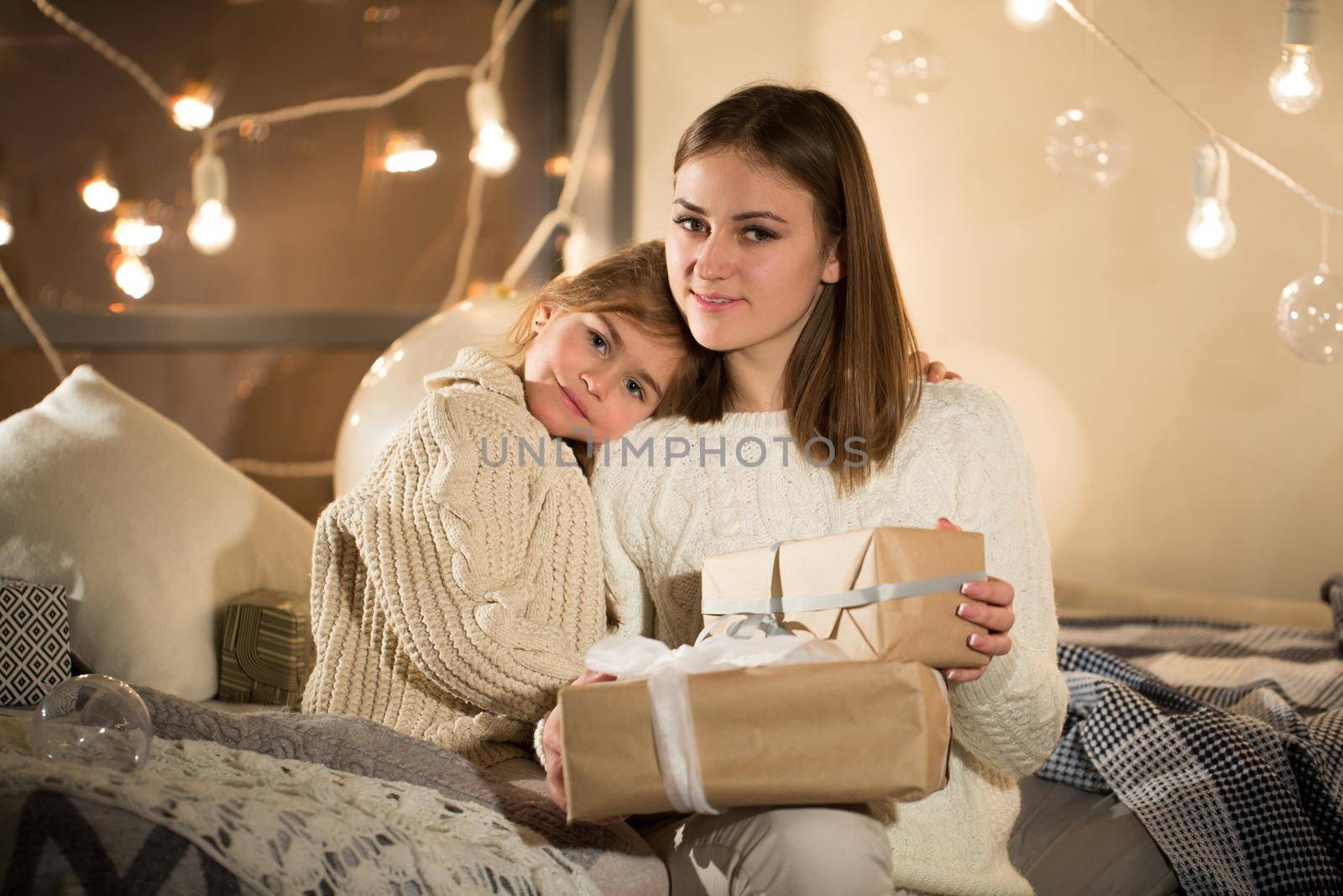 Beautiful mother and daughter opening a magical Christmas gift in the cozy interior of the house. New year