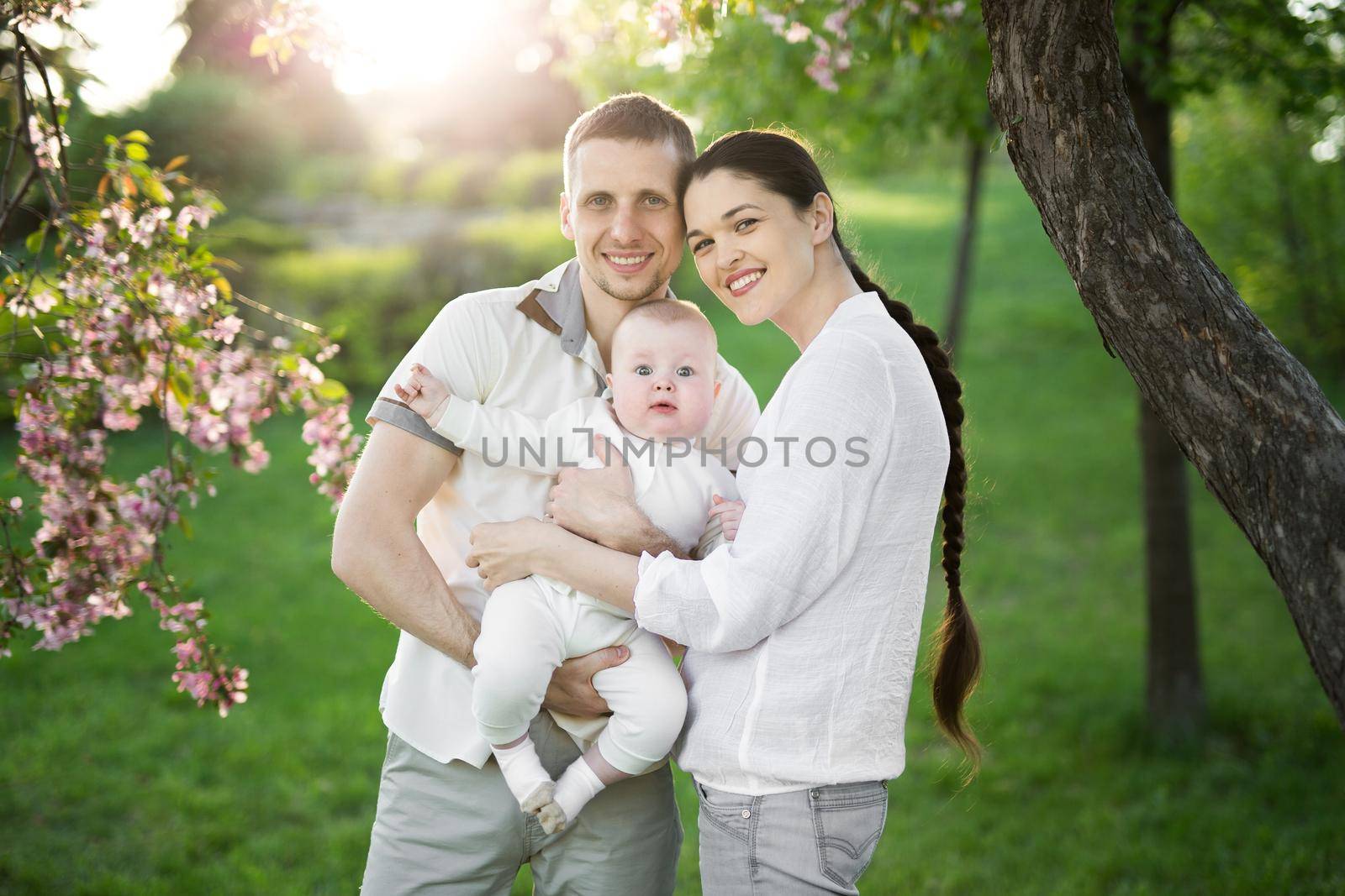 Portrait of a young family with a child. Happy young family spending time outdoor on a summer day. Happiness and harmony in family life. Happy family concept by StudioPeace