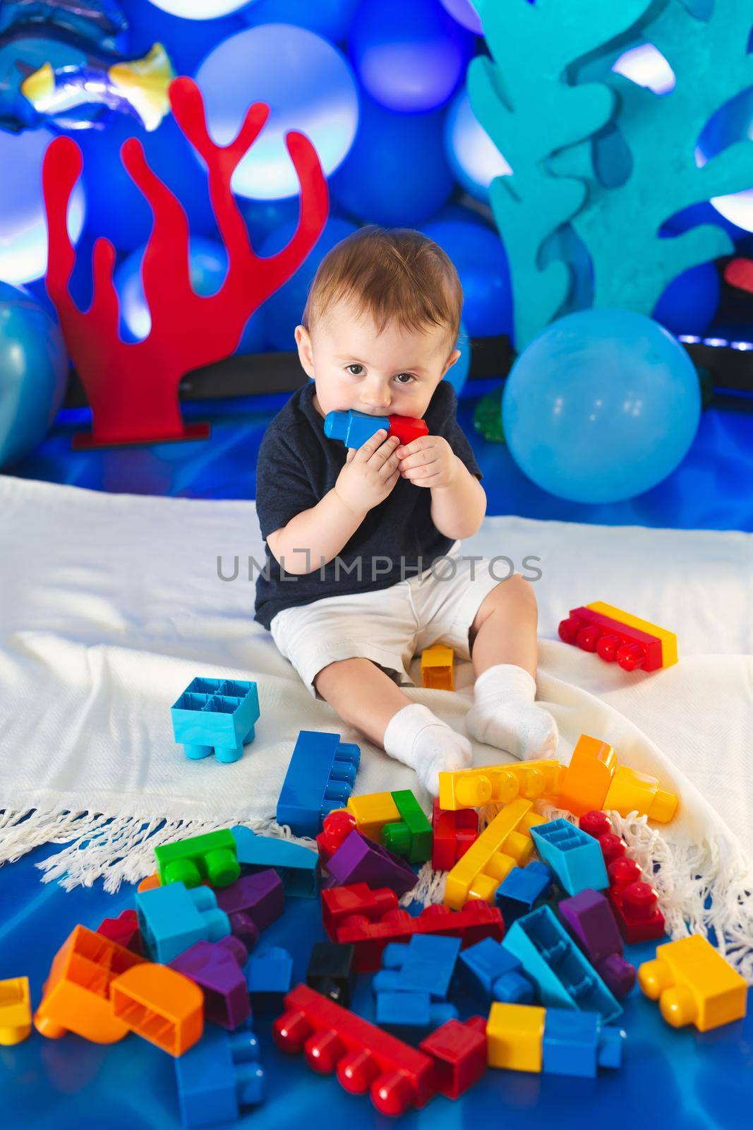 Small boy in a smart suit sits on the floor and plays with a construction kit.