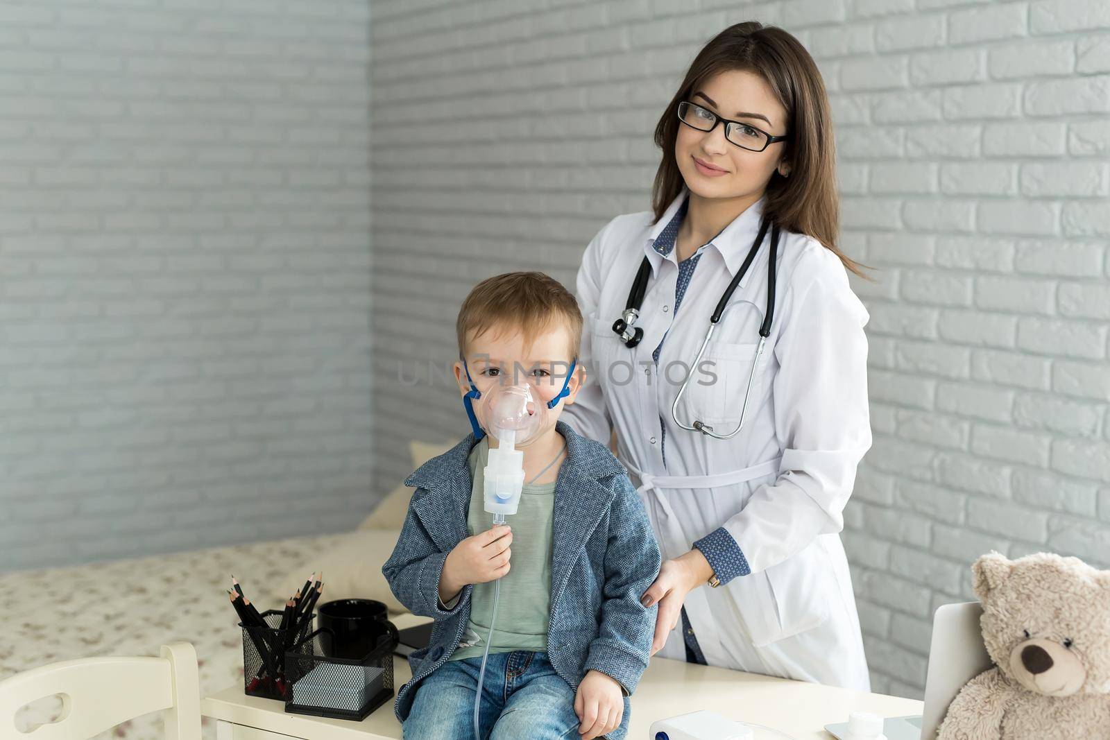 Medical doctor applying medicine inhalation treatment on a little boy with asthma inhalation therapy by the mask of inhaler by StudioPeace