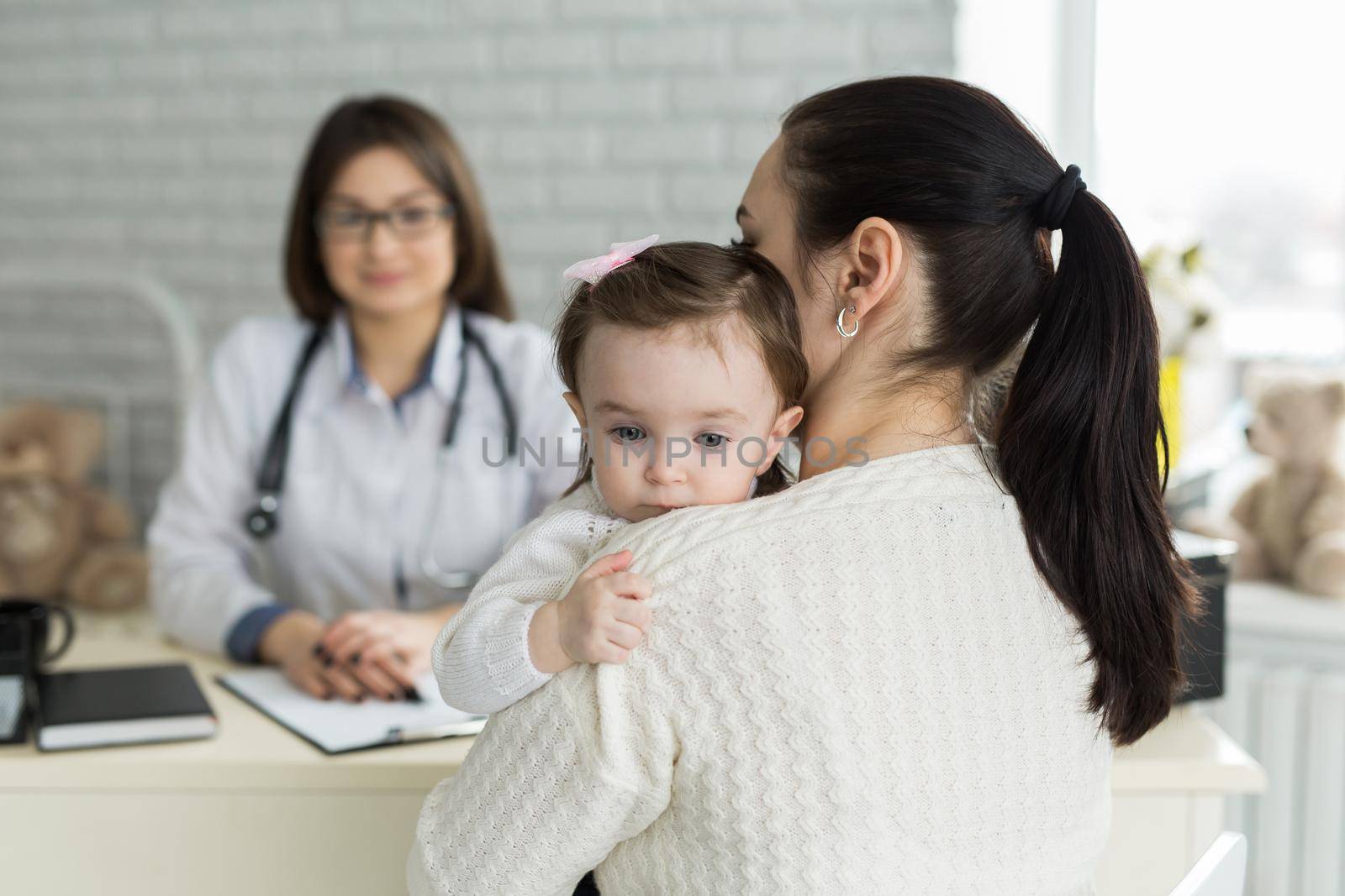 Portrait of mother and child at a doctor's appointment. Pediatrician meeting with mother and child in hospital by StudioPeace