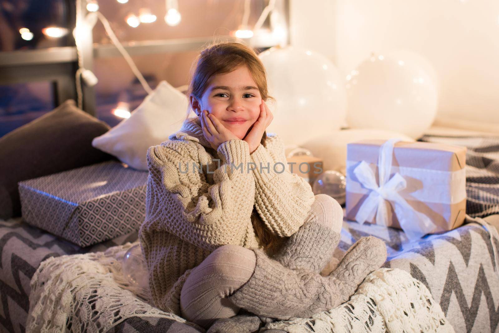Beautiful little girl sitting on bed with a gift in its hands