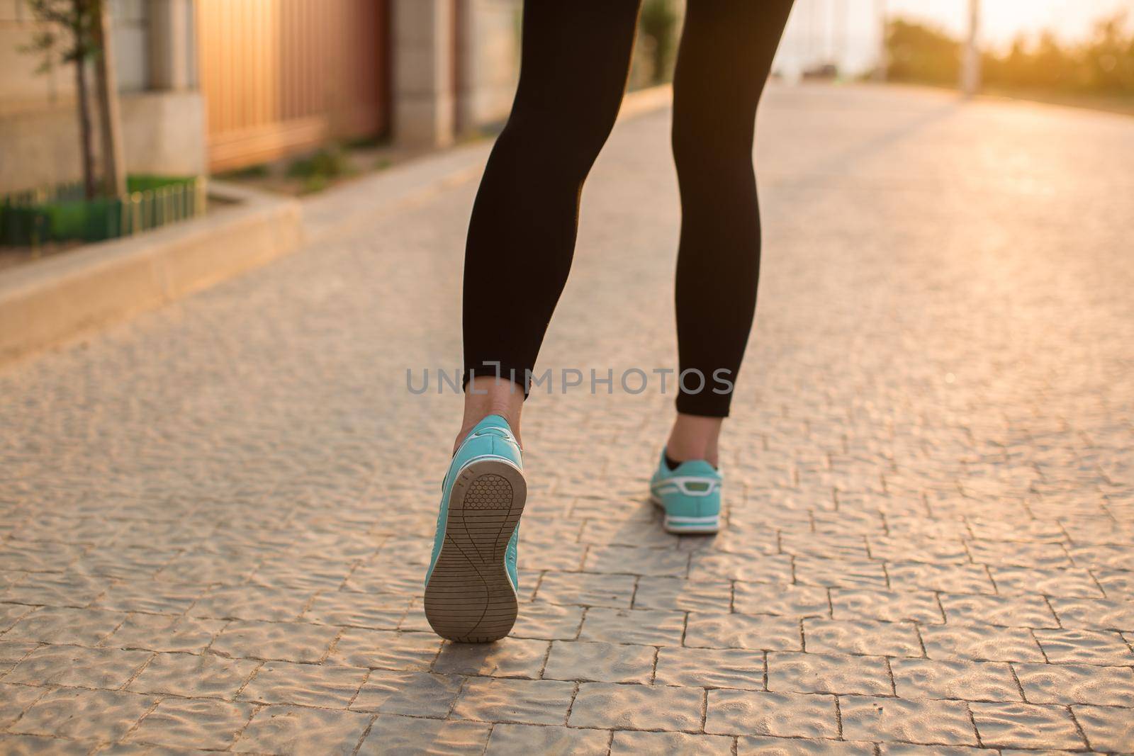 Athlete runner feet running on road closeup on shoe. woman fitness sunrise jog workout wellness concept by StudioPeace
