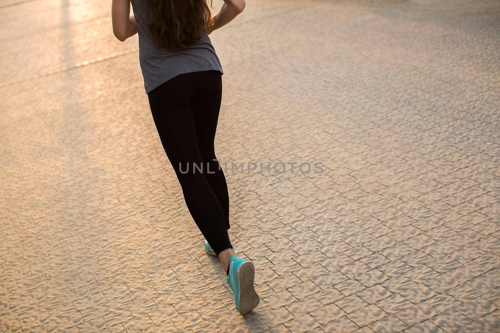 Athlete runner feet running on road closeup on shoe. woman fitness sunrise jog workout wellness concept.