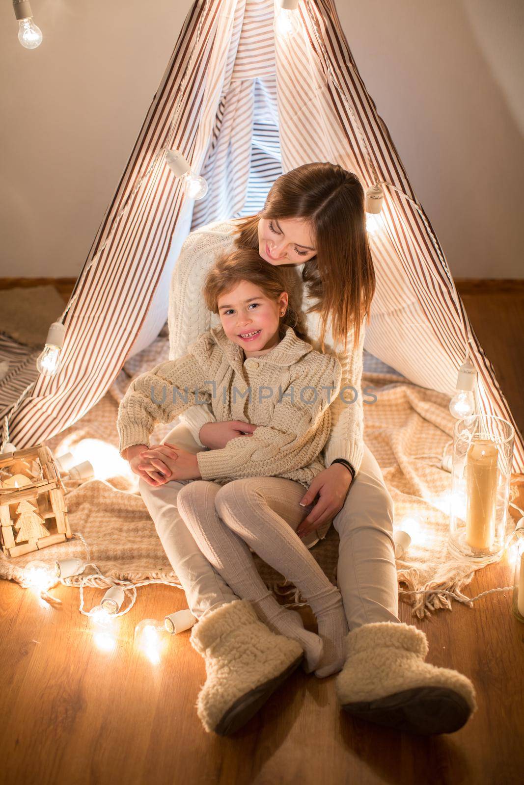 Beautiful mother and daughter, Christmas eve, sitting in the cosy interior. New year. by StudioPeace