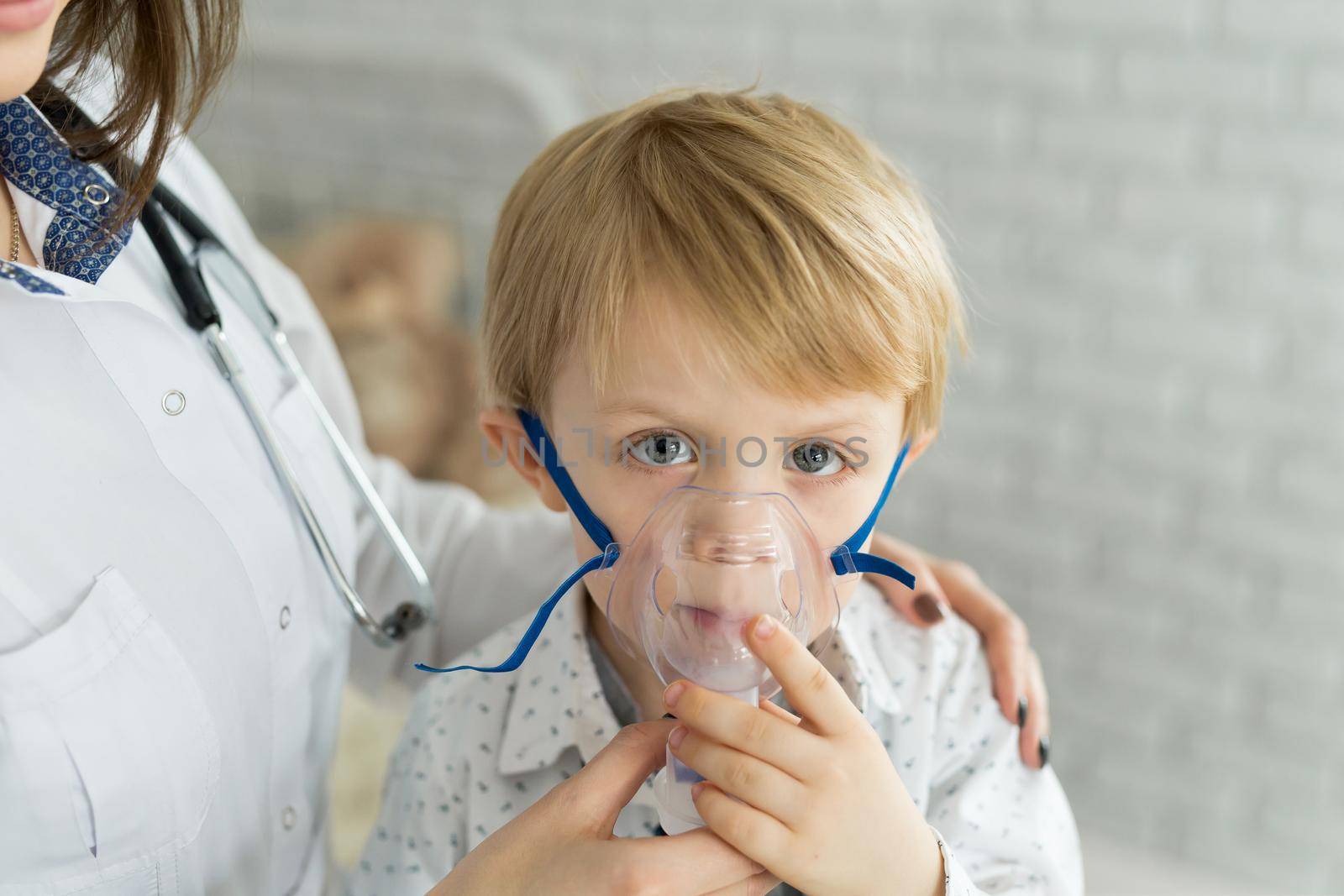 Medical doctor applying medicine inhalation treatment on a little boy with asthma inhalation therapy by the mask of inhaler by StudioPeace