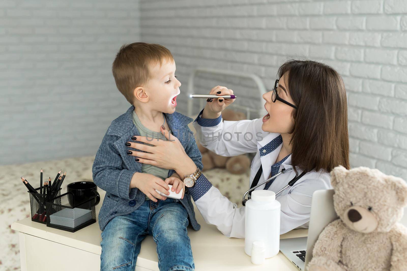Doctor examine child's throat. Boy at pediatrician office by StudioPeace