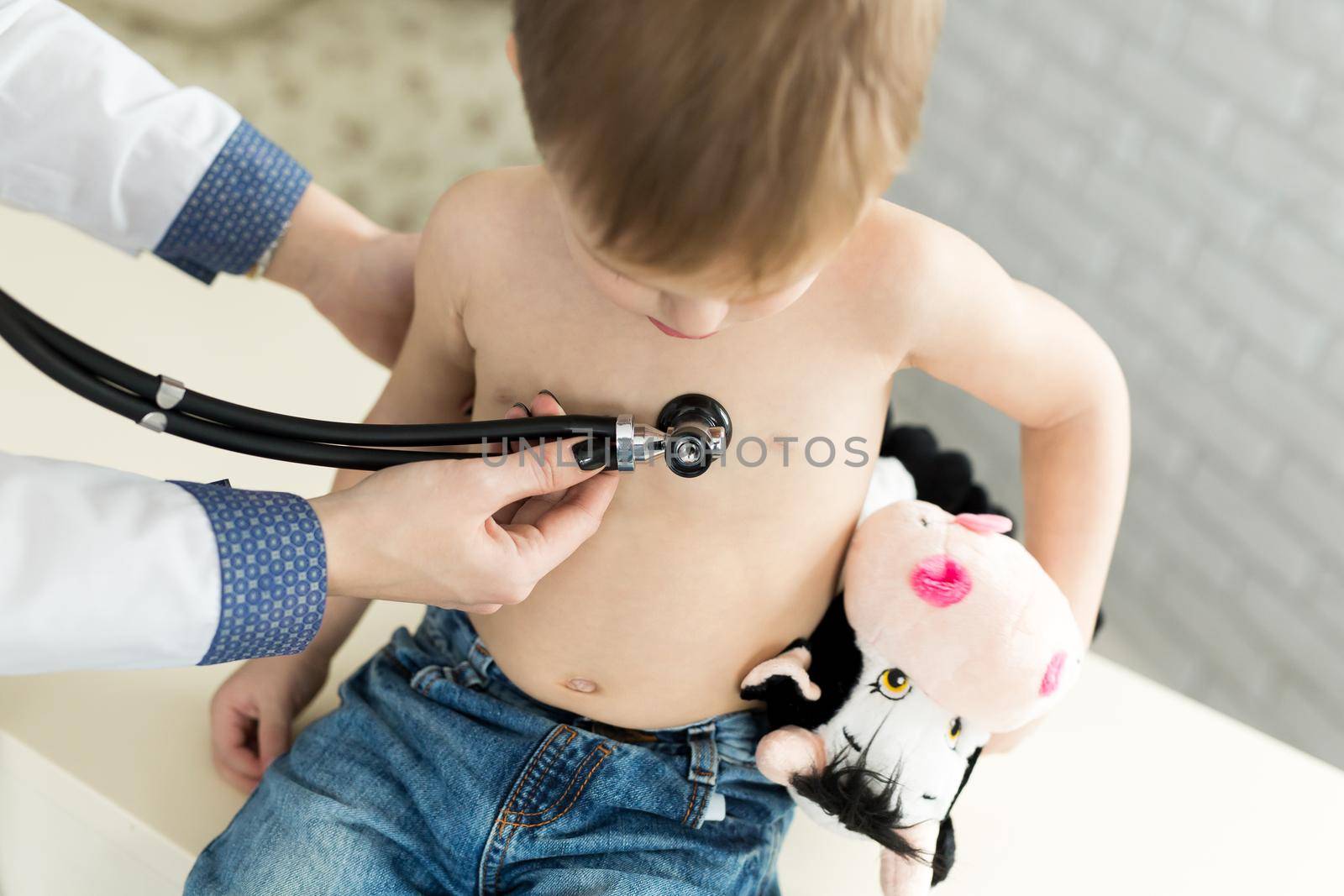 Professional general medical pediatrician doctor in white uniform gown listen lung and heart sound of child patient with stethoscope by StudioPeace